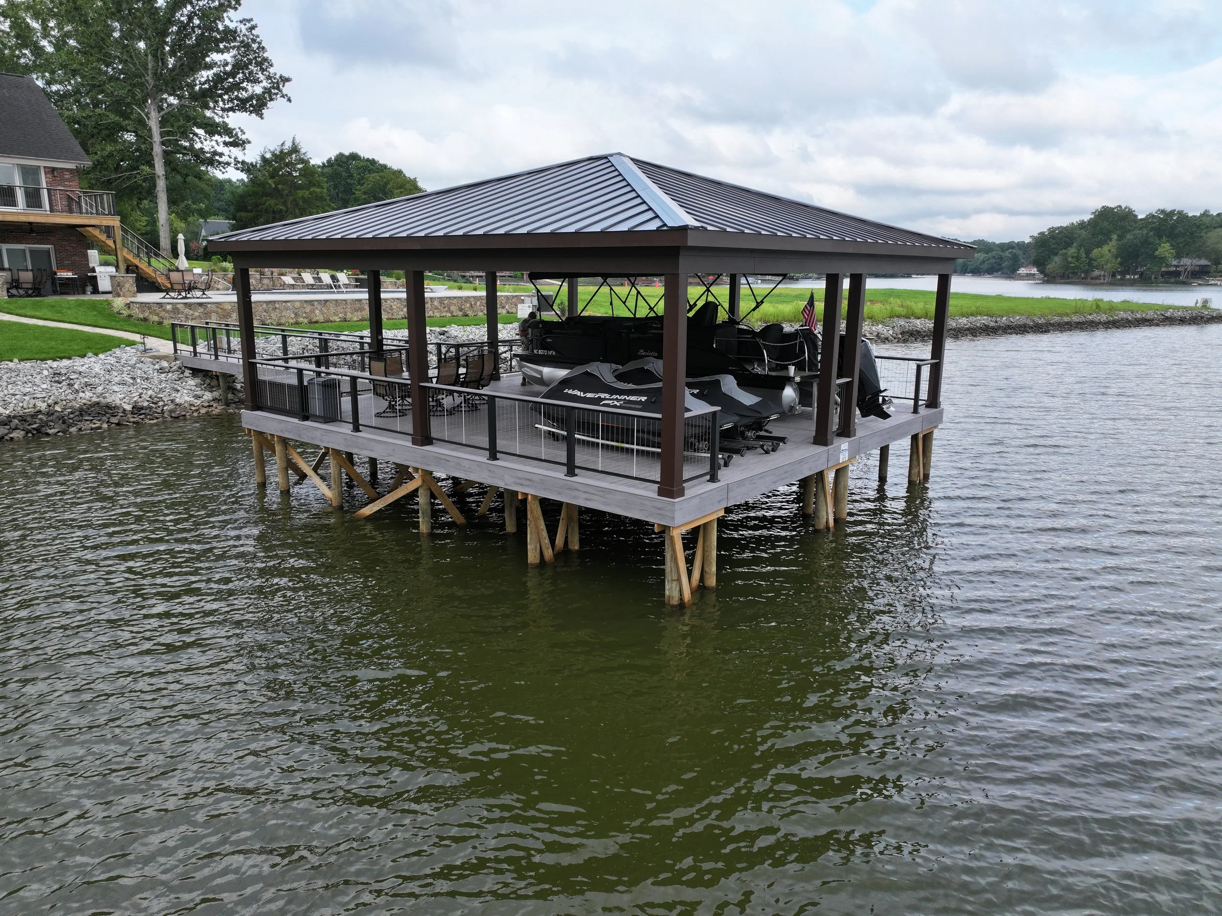 A lake house with a dock and boat storage area on a cloudy day.