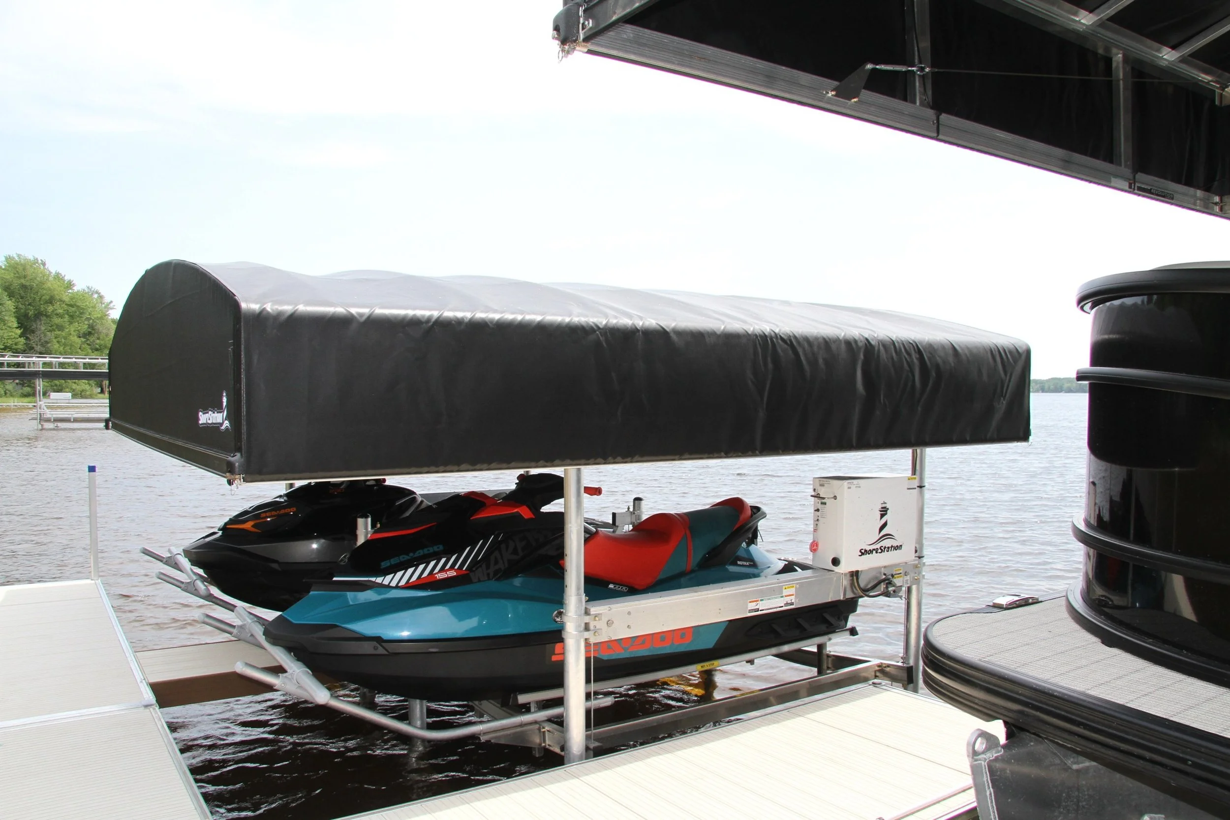 A dockside boat lift holding a jet ski, a personal watercraft, next to a body of water with trees in the background.