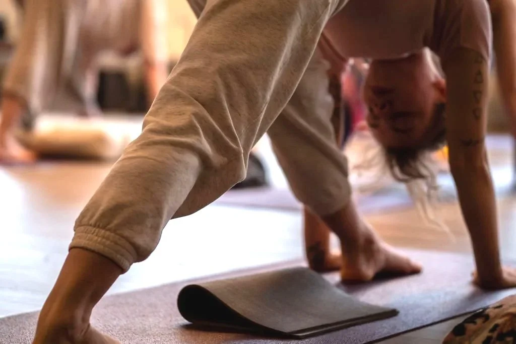 Person in a yoga pose on a mat, with one leg bent and one arm on the floor, in a room with a wooden floor.