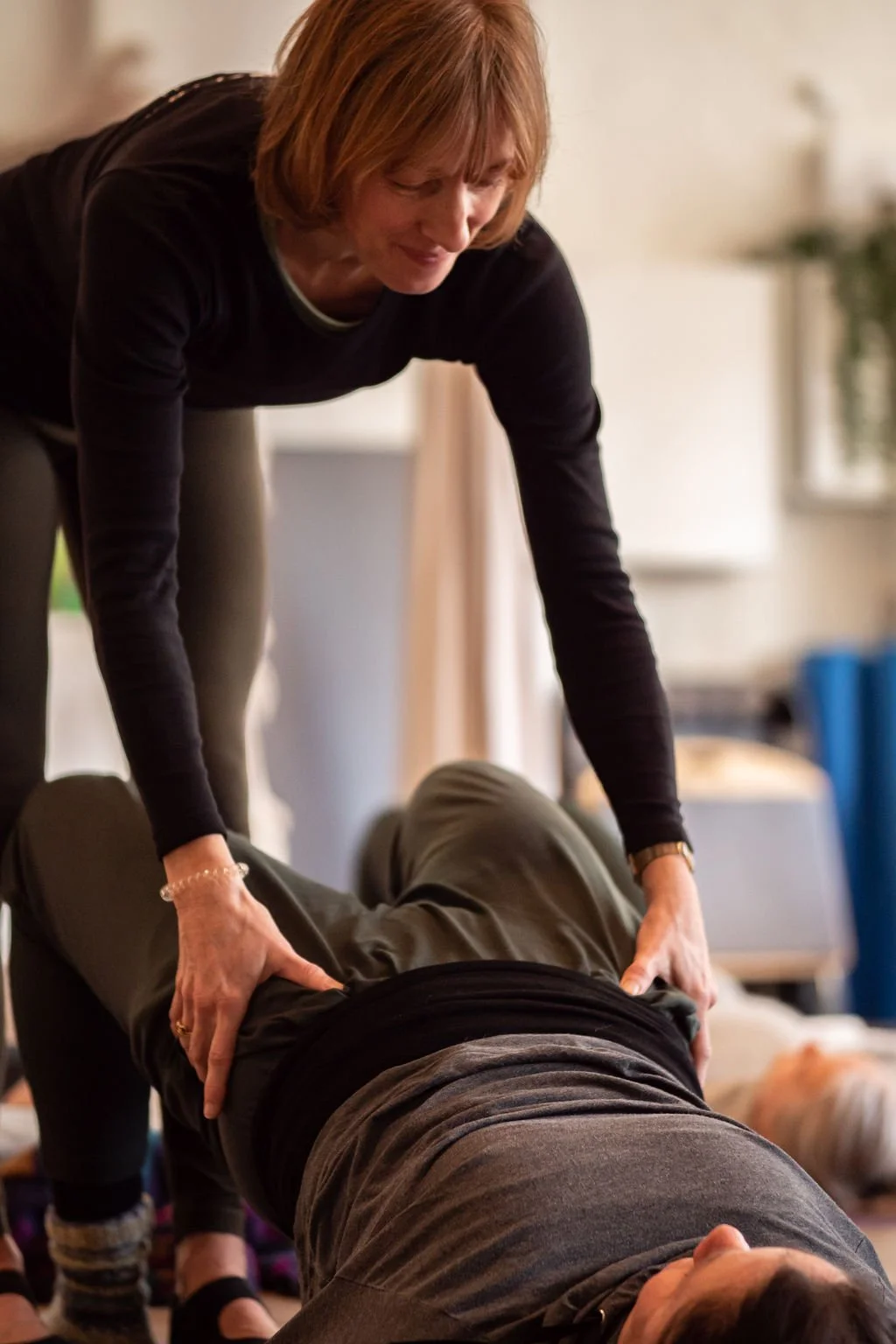 Woman performing chest compressions during CPR training on a man lying on the floor.
