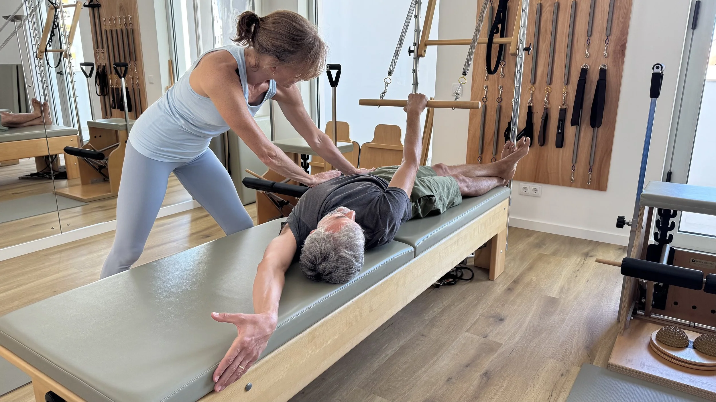 A physical therapist assisting an elderly woman with leg exercises on a treatment table in a therapy clinic.