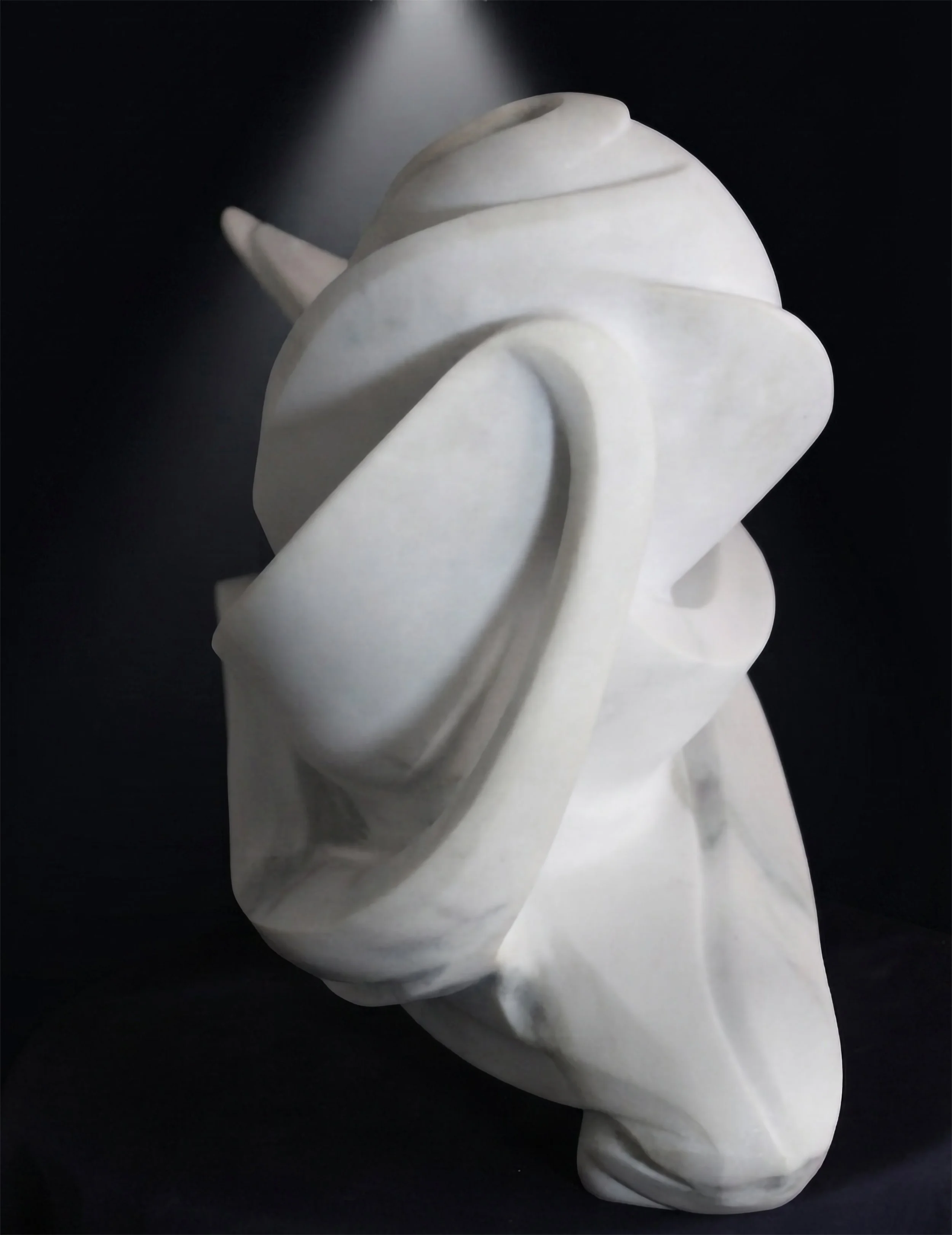 Detalle de la talla a mano en la escultura 'Ondas' de Raúl Abad. El trabajo artesanal sobre el mármol blanco resalta la pureza y las formas orgánicas de la pieza. Coleccionista de arte.
