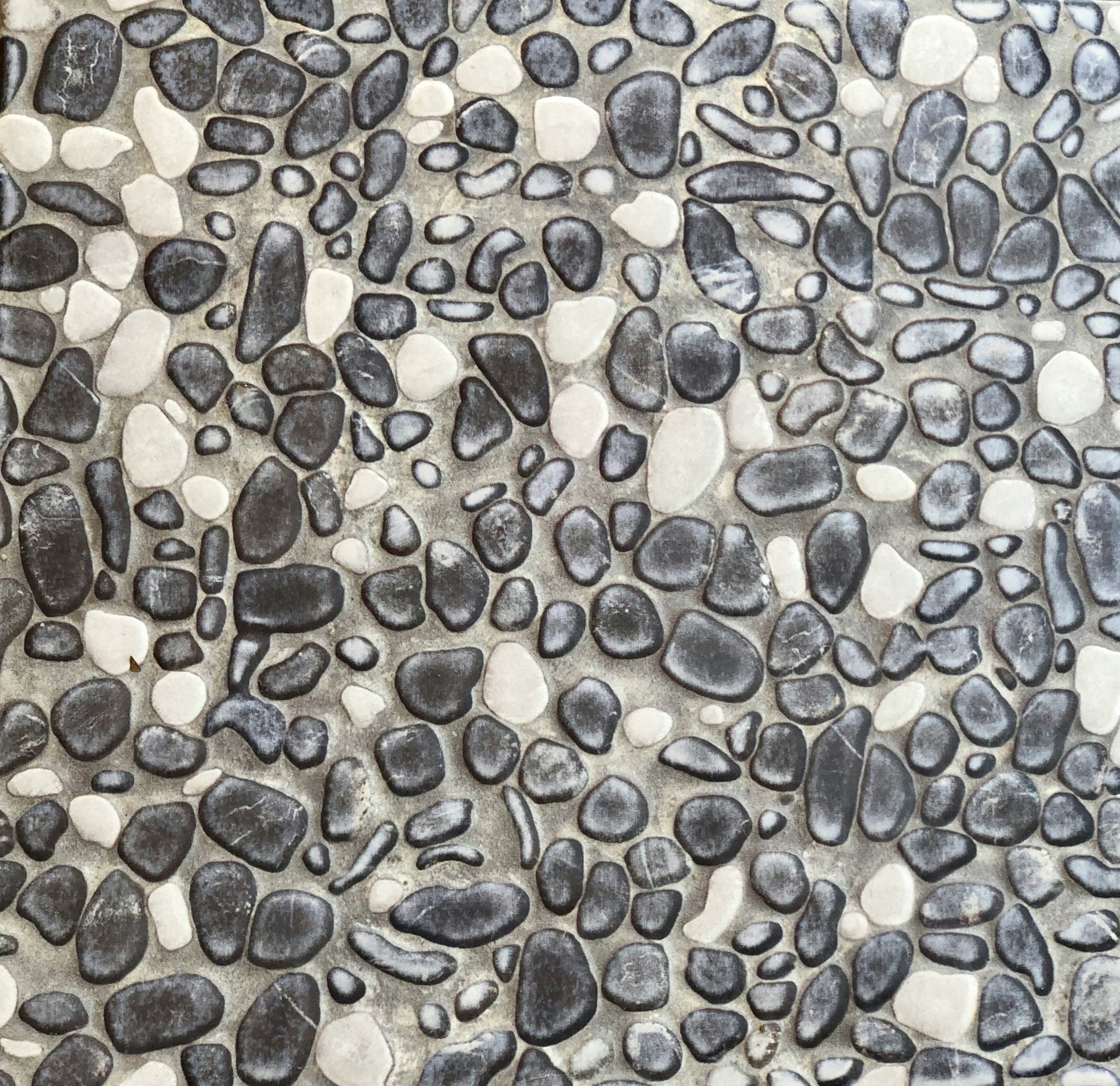 Close-up of a pebble mosaic flooring with various dark and light stones arranged randomly.