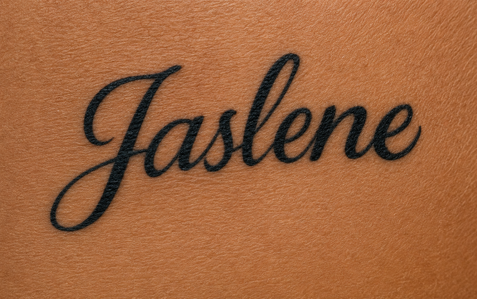 A close-up of a tattoo of the name 'Jasene' in cursive black ink on skin.