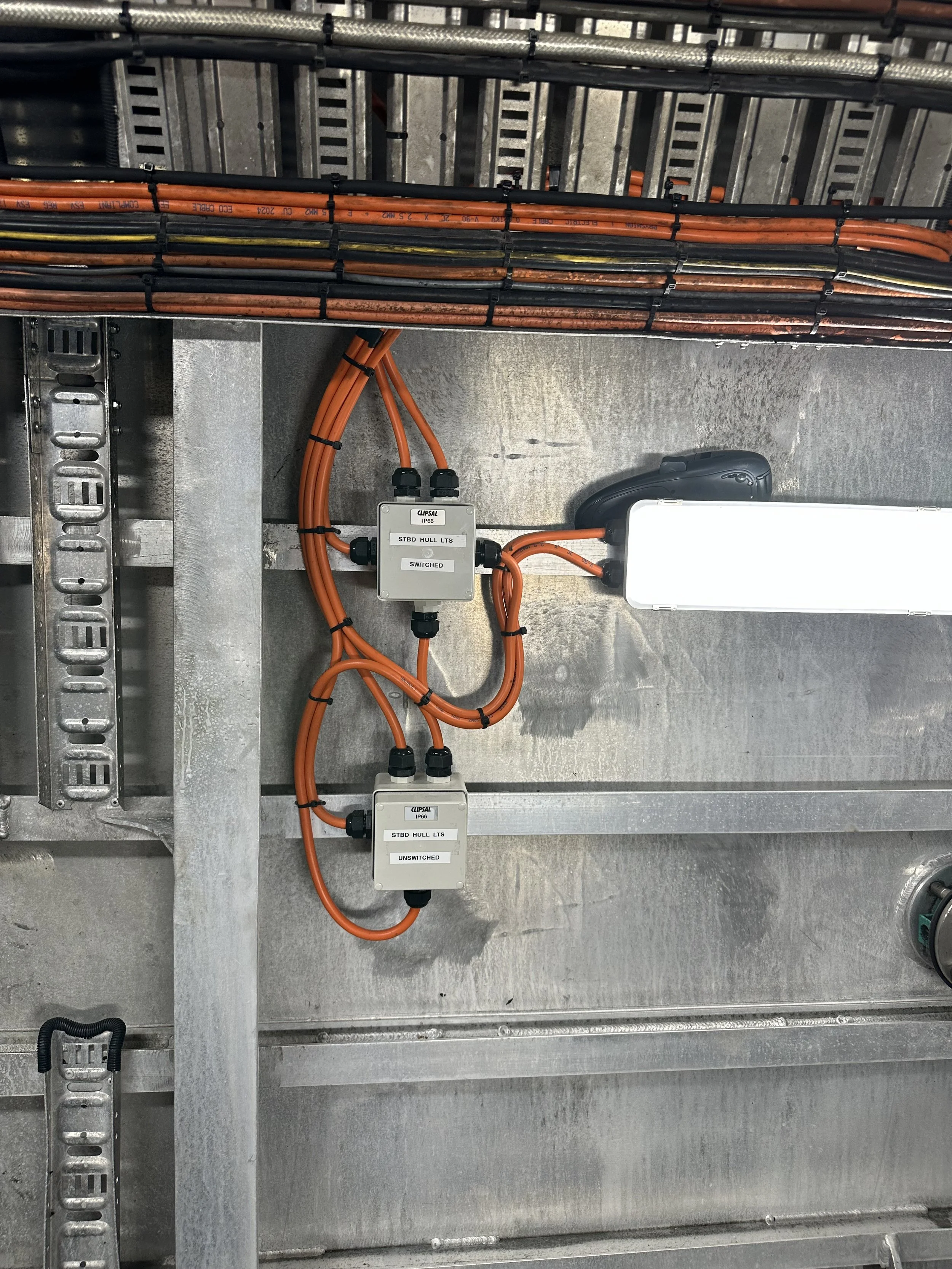 Electrical wiring and control panels installed on a metallic wall structure in an industrial setting.