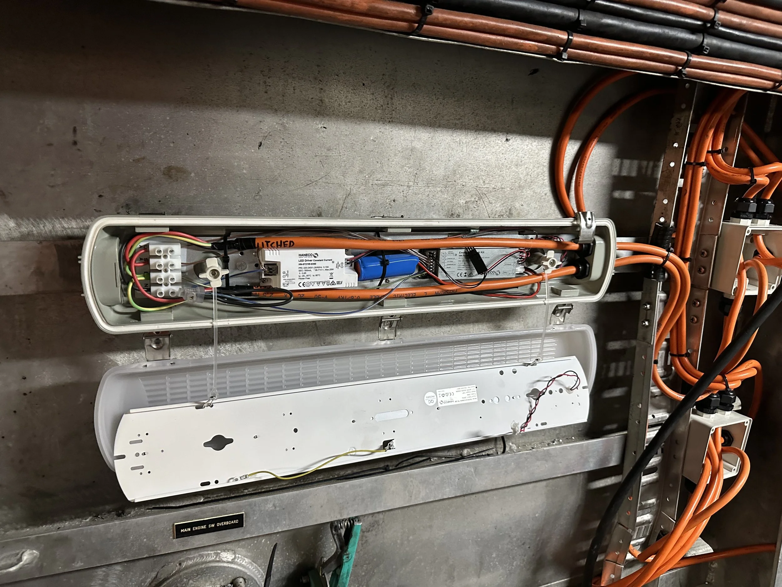 Interior of an electrical or electronic system enclosure showing wiring, circuit boards, and components with orange wiring and metal framework.