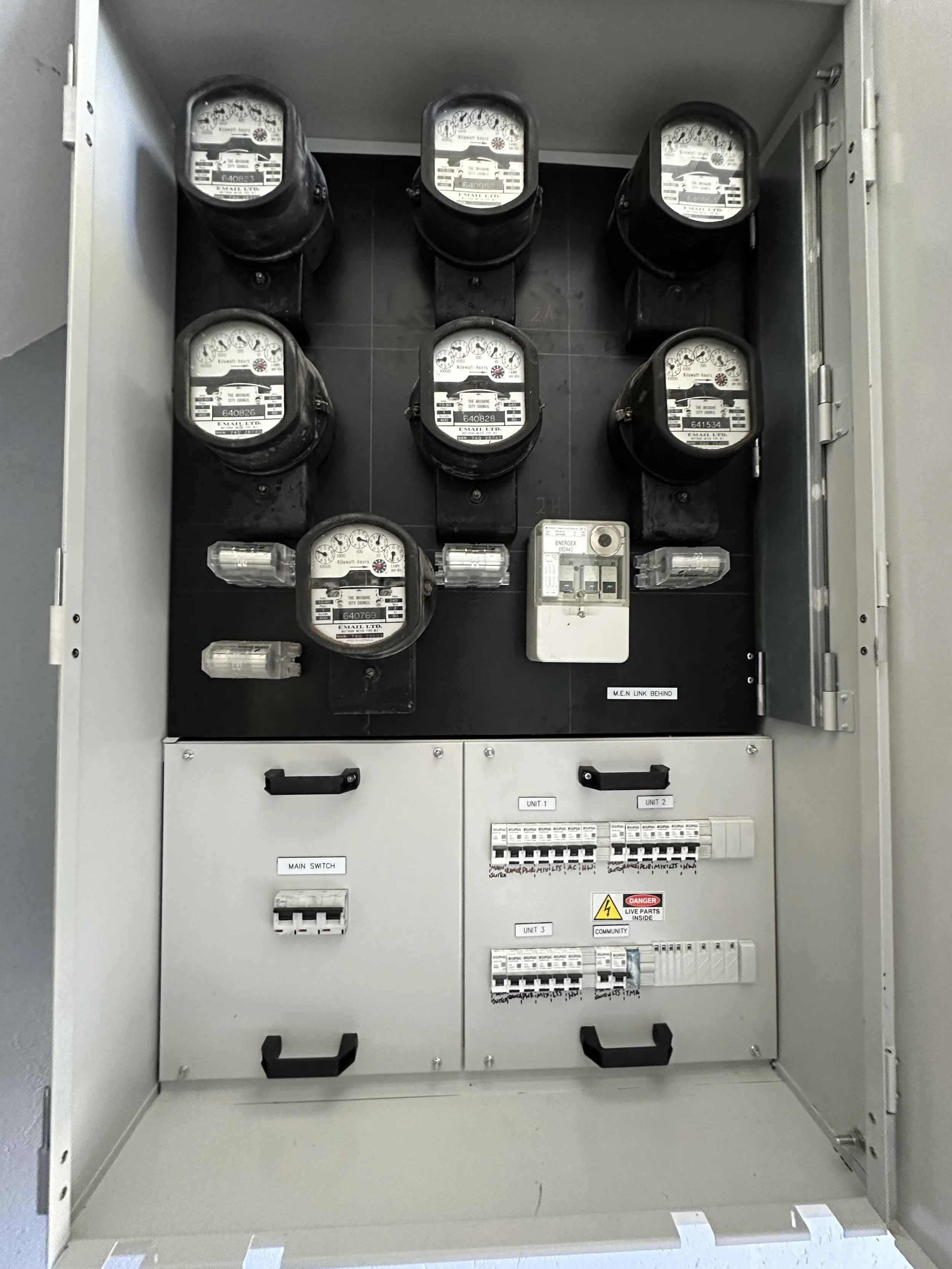 An electrical panel with several circuit breakers, labeled sections, and digital and analog meters inside.