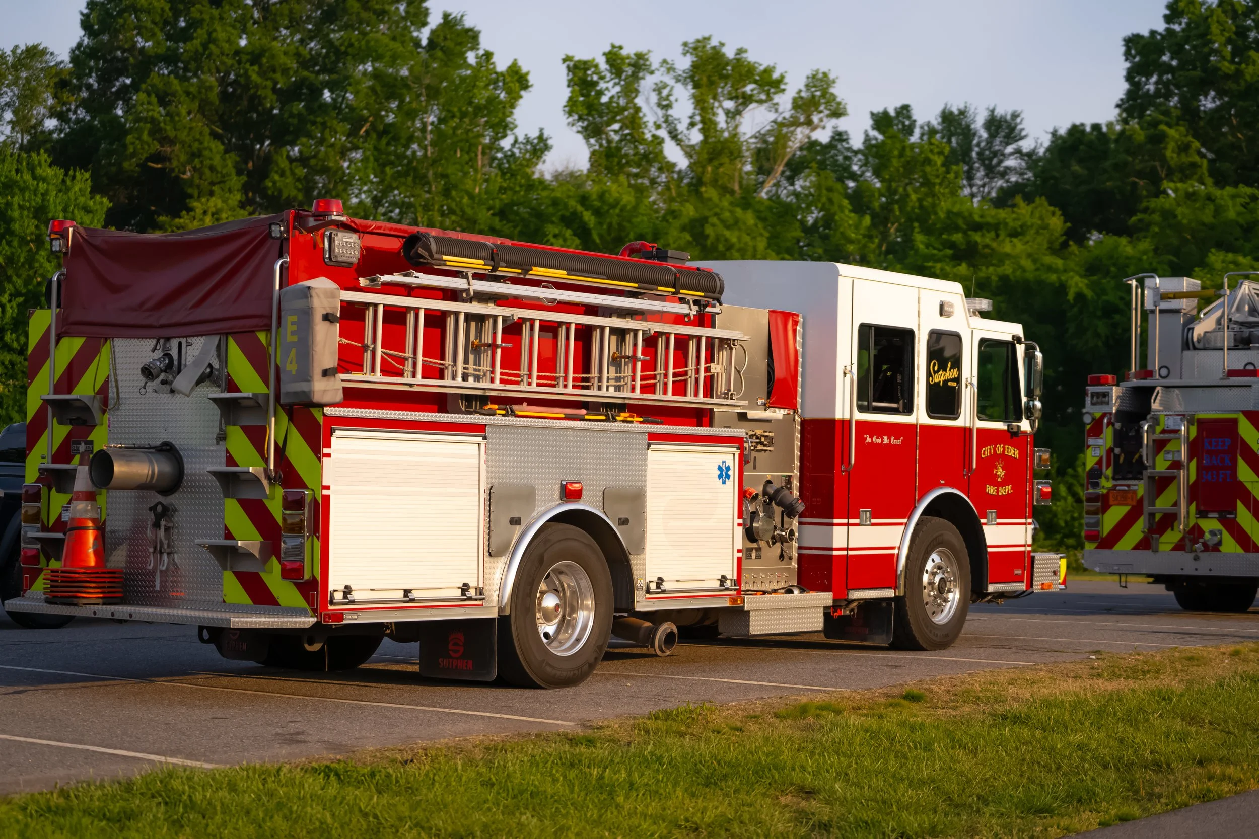 Red fire truck parked outdoors with trees in the background.