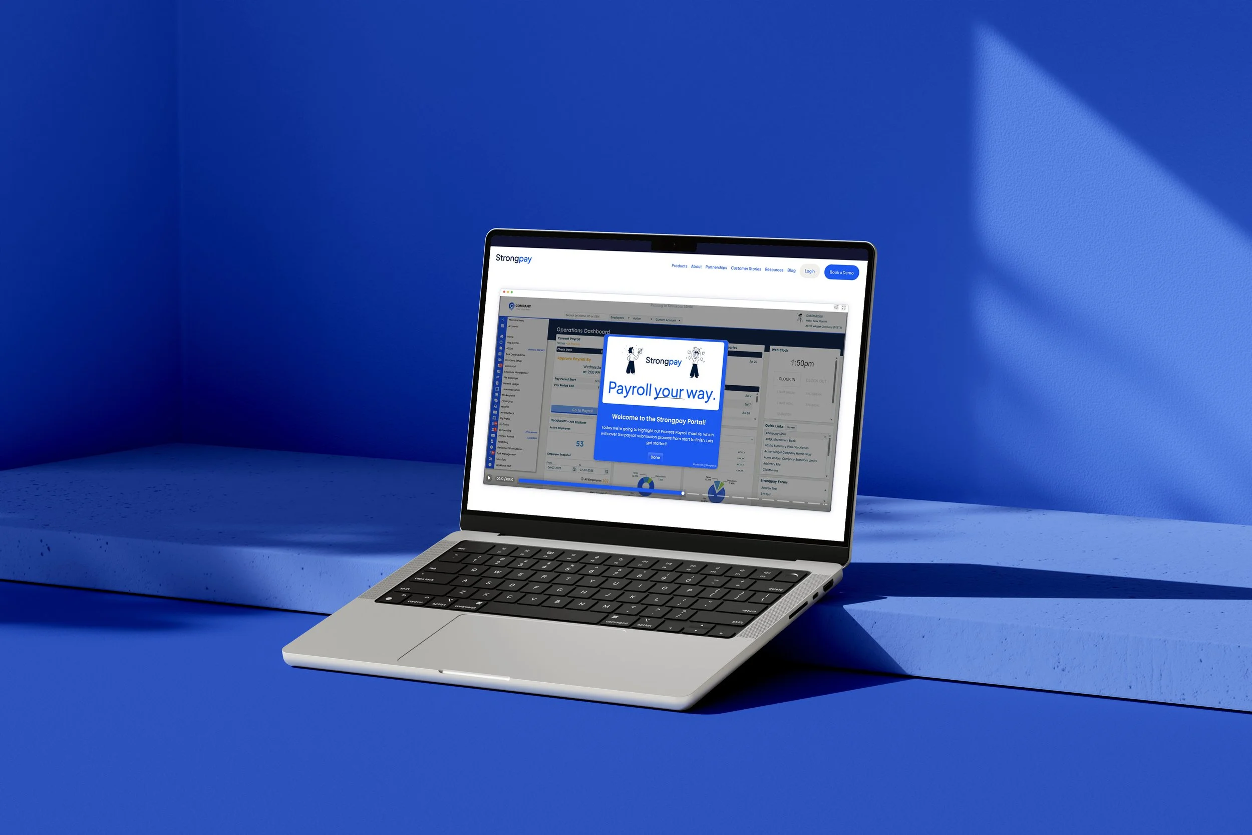 A silver laptop on a blue surface with a blue wall background, displaying a webpage from Strongpay with payroll management features.