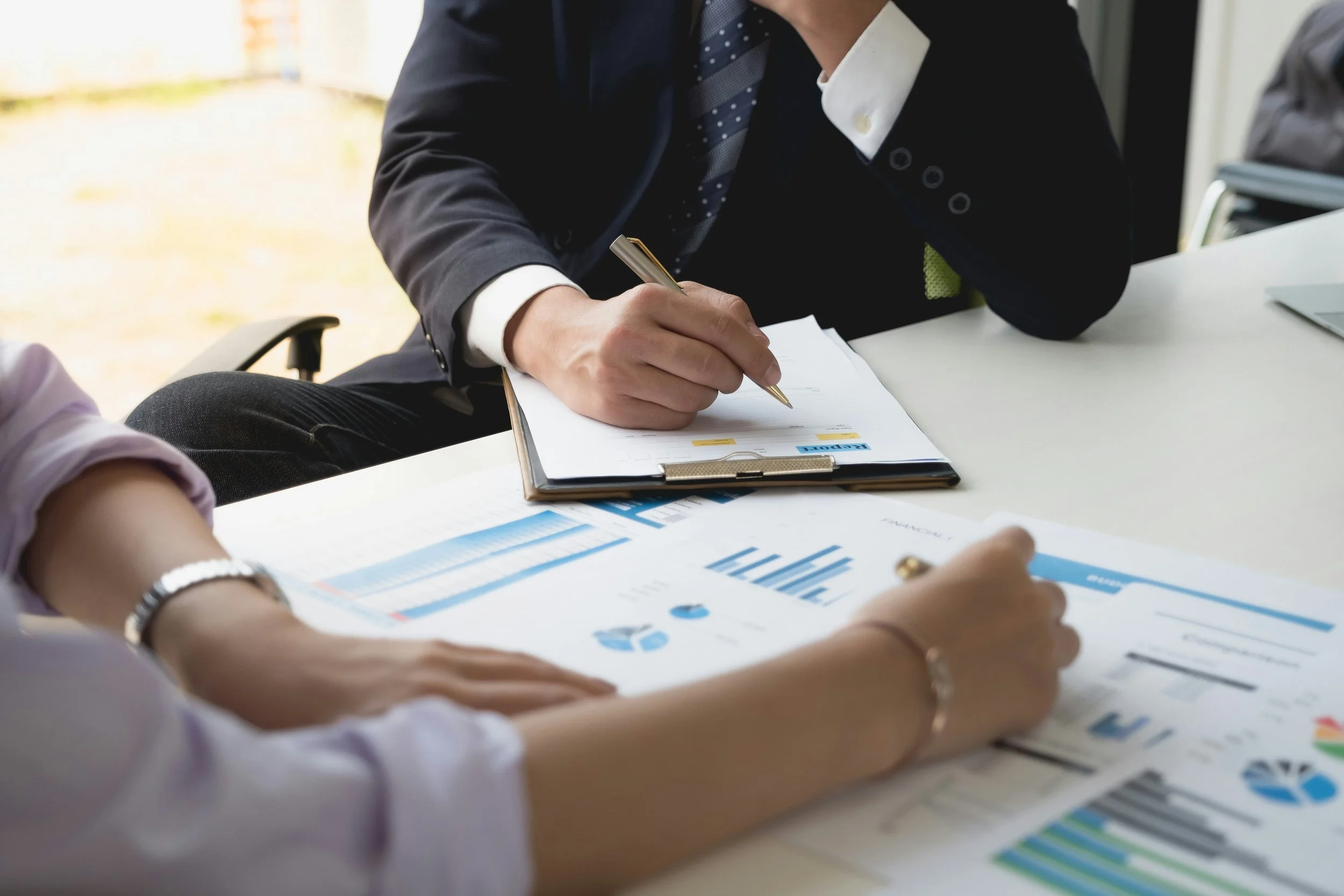 Businesspeople sitting at a table with financial charts and documents, discussing and analyzing data.