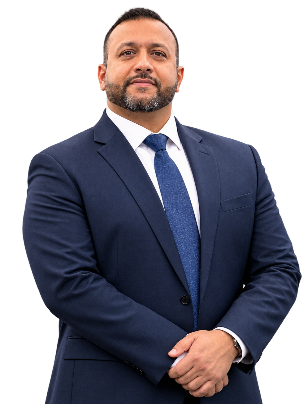 A confident man in a navy blue suit, white shirt, and blue tie standing with arms crossed, against a plain background.