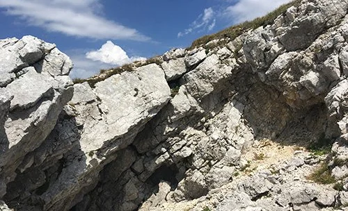 Falaise rocheuse sous un ciel partiellement nuageux.