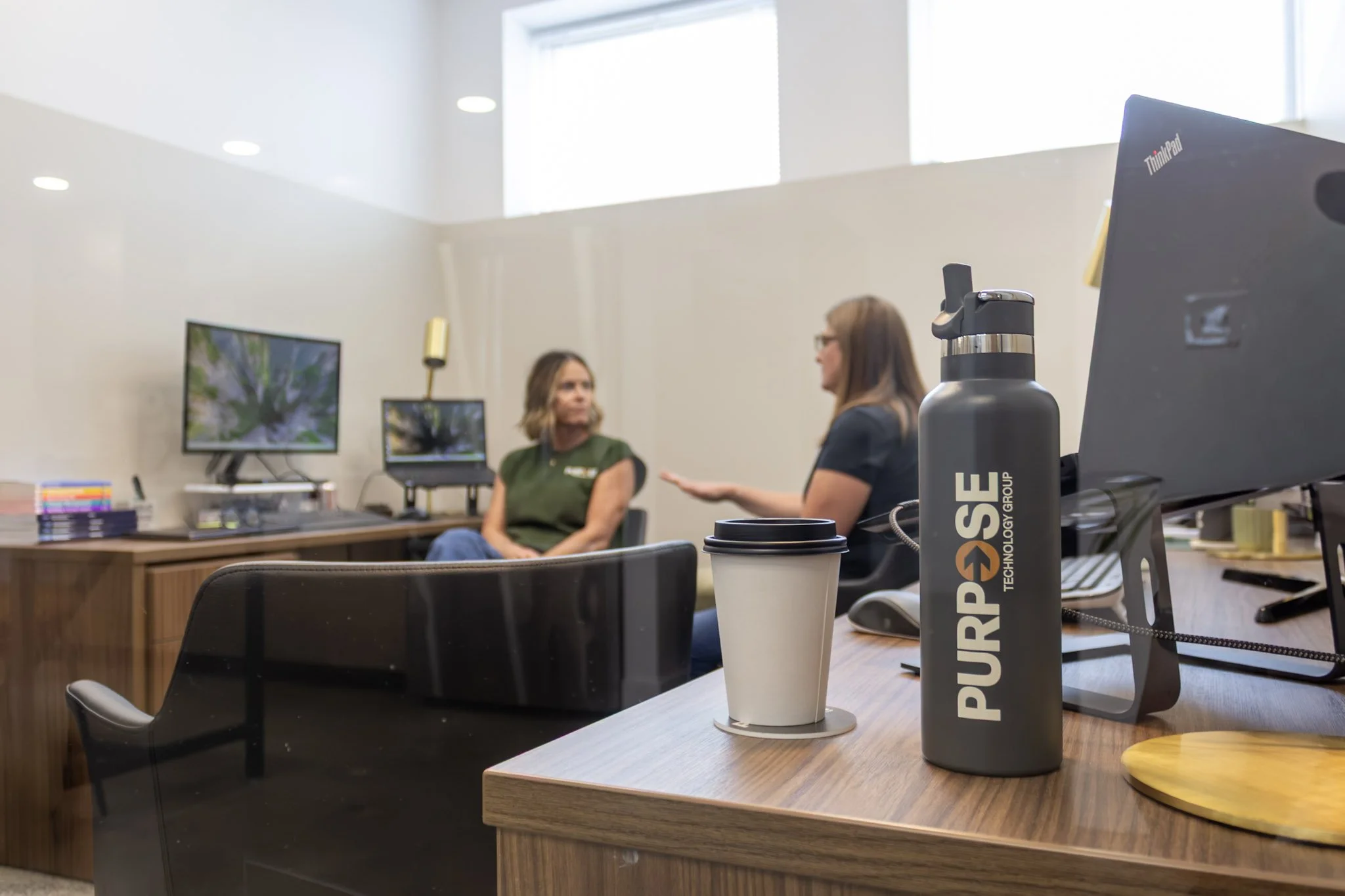 A team of two people in an office talking to show Co-Mananged technology from Purpose Technology Group