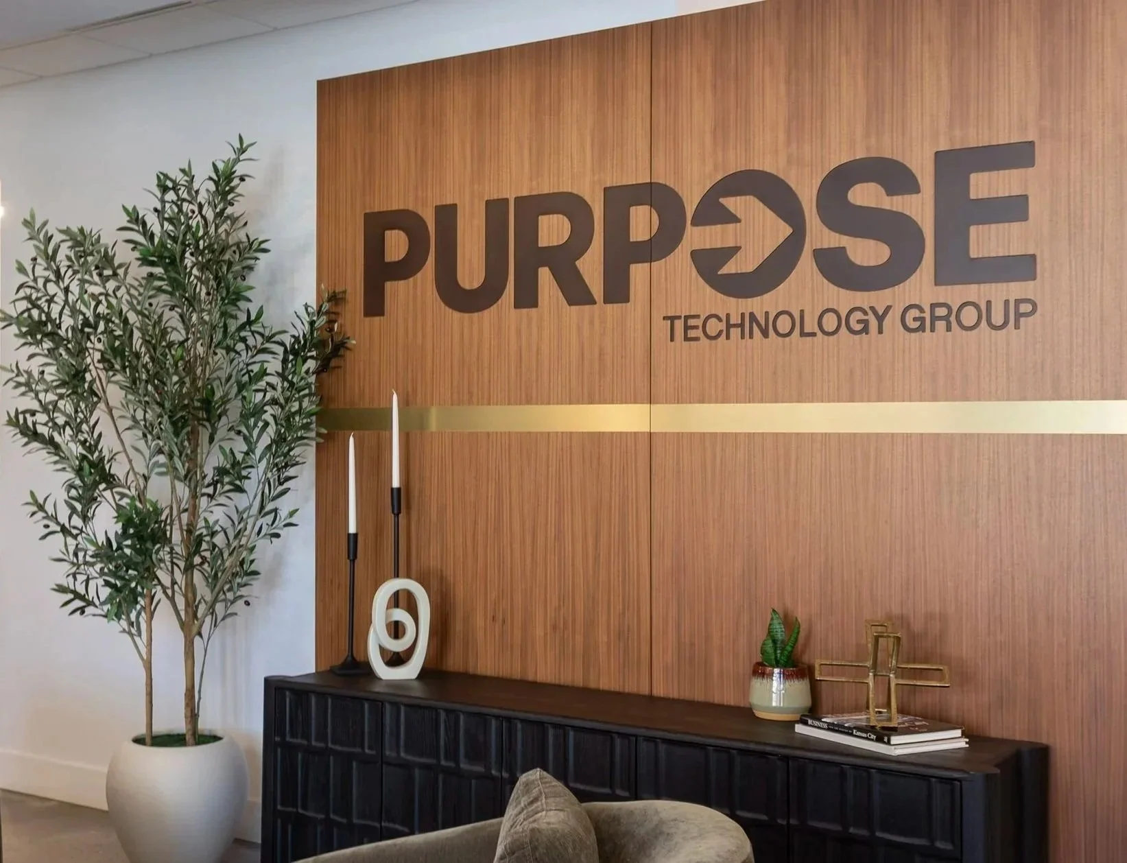 A photograph of Purpose Technology Group's front entrance lobby with a large wood wall engraved with their logo.