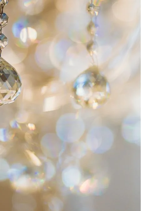 Close-up of hanging crystal beads and light reflections, creating a sparkling, bokeh effect.