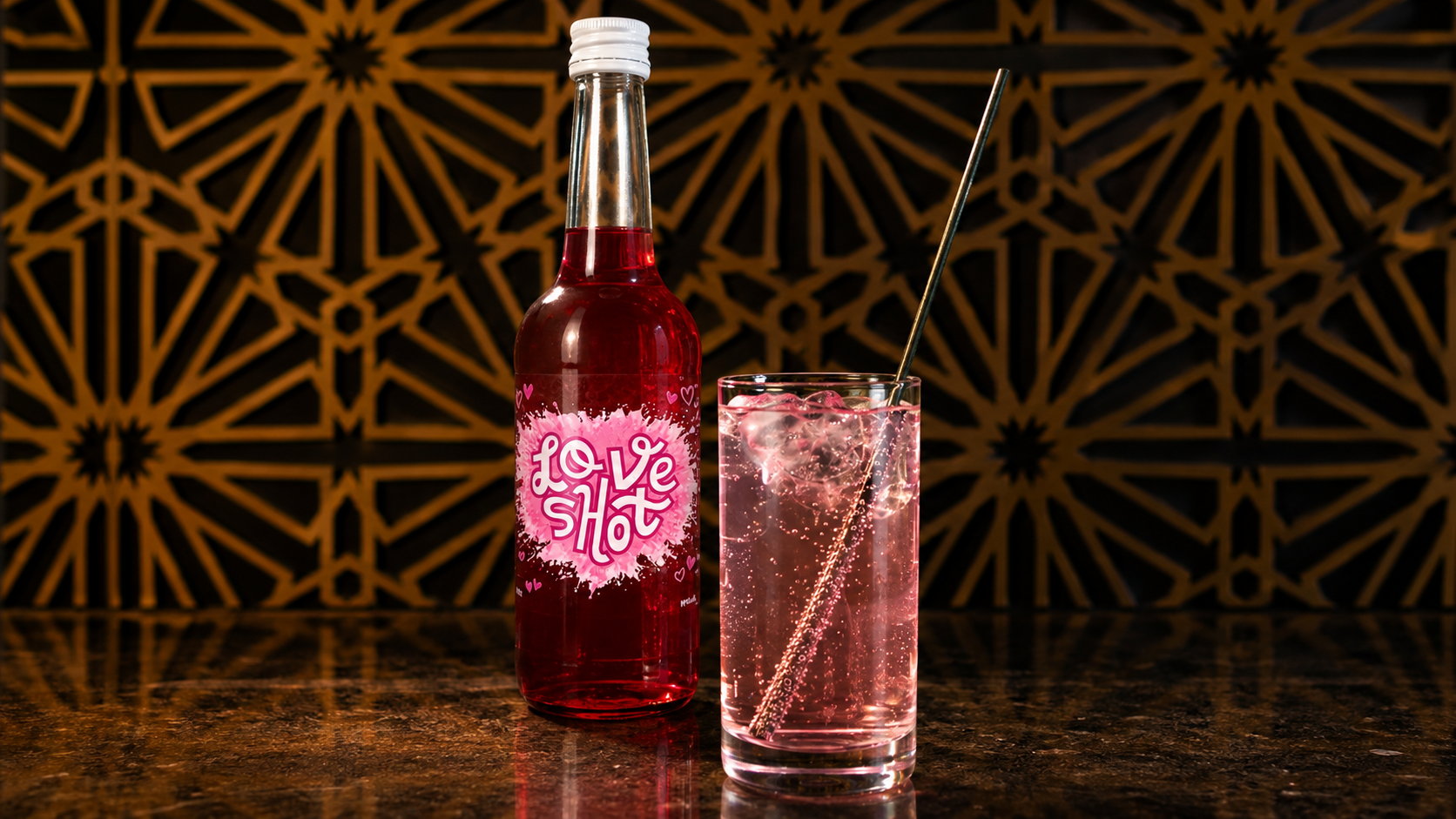 Een fles met het label 'Love Shot' en een glas met roze drankje en een rietje, op een marmeren tafel tegen een decoratief zwart-goud patroon