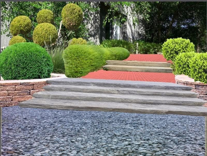 A garden pathway with stone steps leading to a red brick walkway, surrounded by round, well-manicured green bushes and trees.