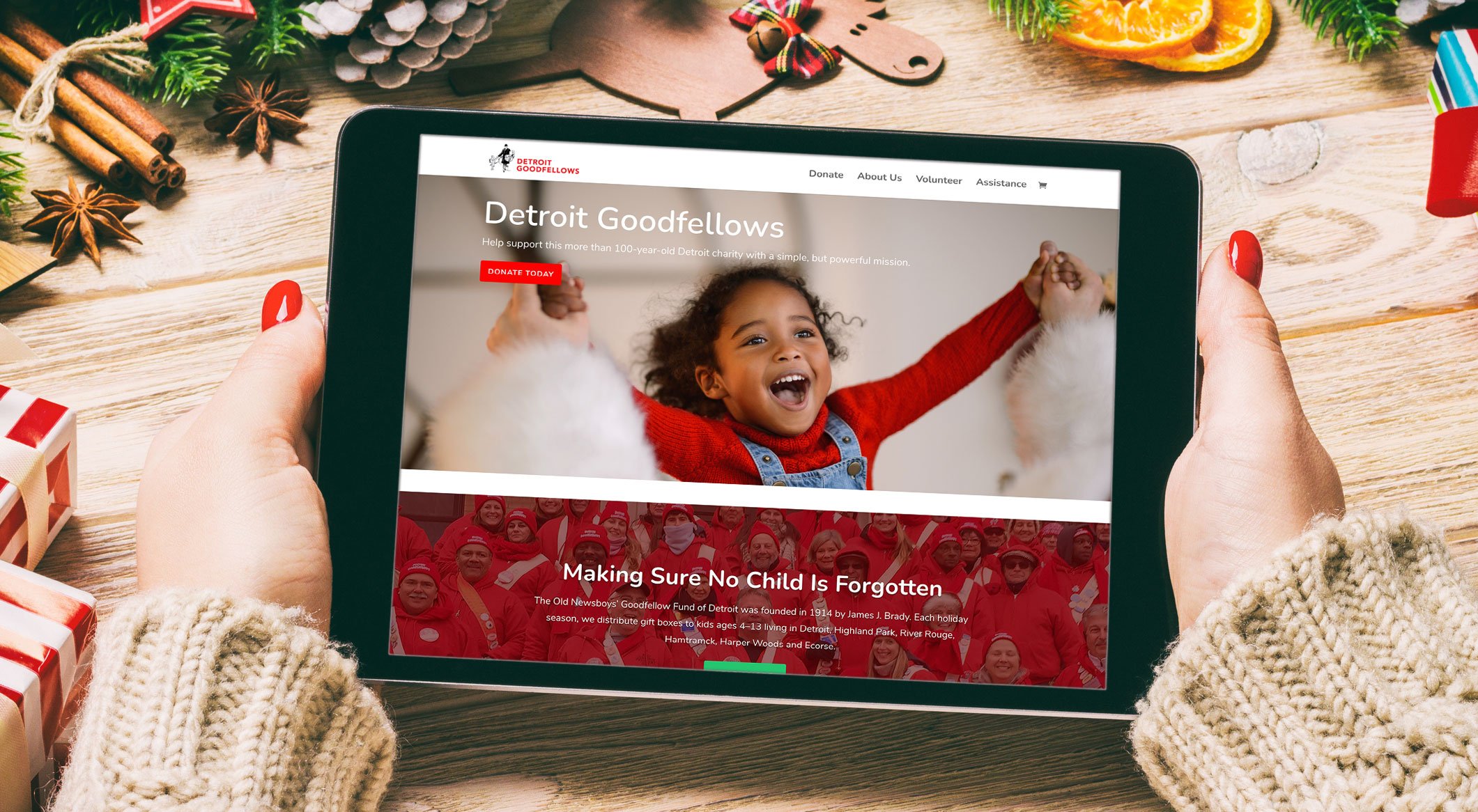 Hands holding a tablet showing the Detroit Goodfellows website.
