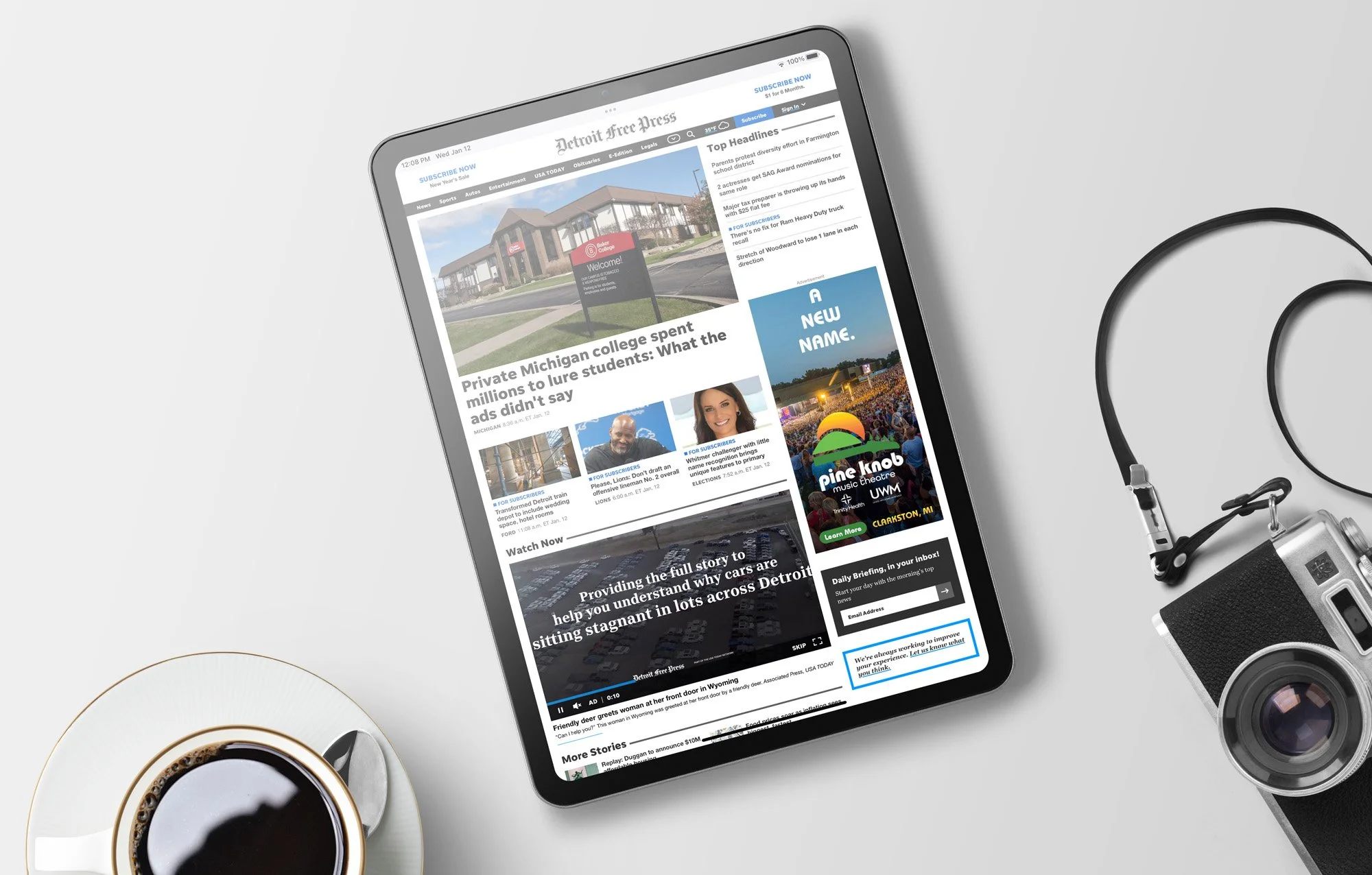 A tablet showing a Detroit Free Press webpage with Pine Knob banner ad. The headline reads, "A new name."