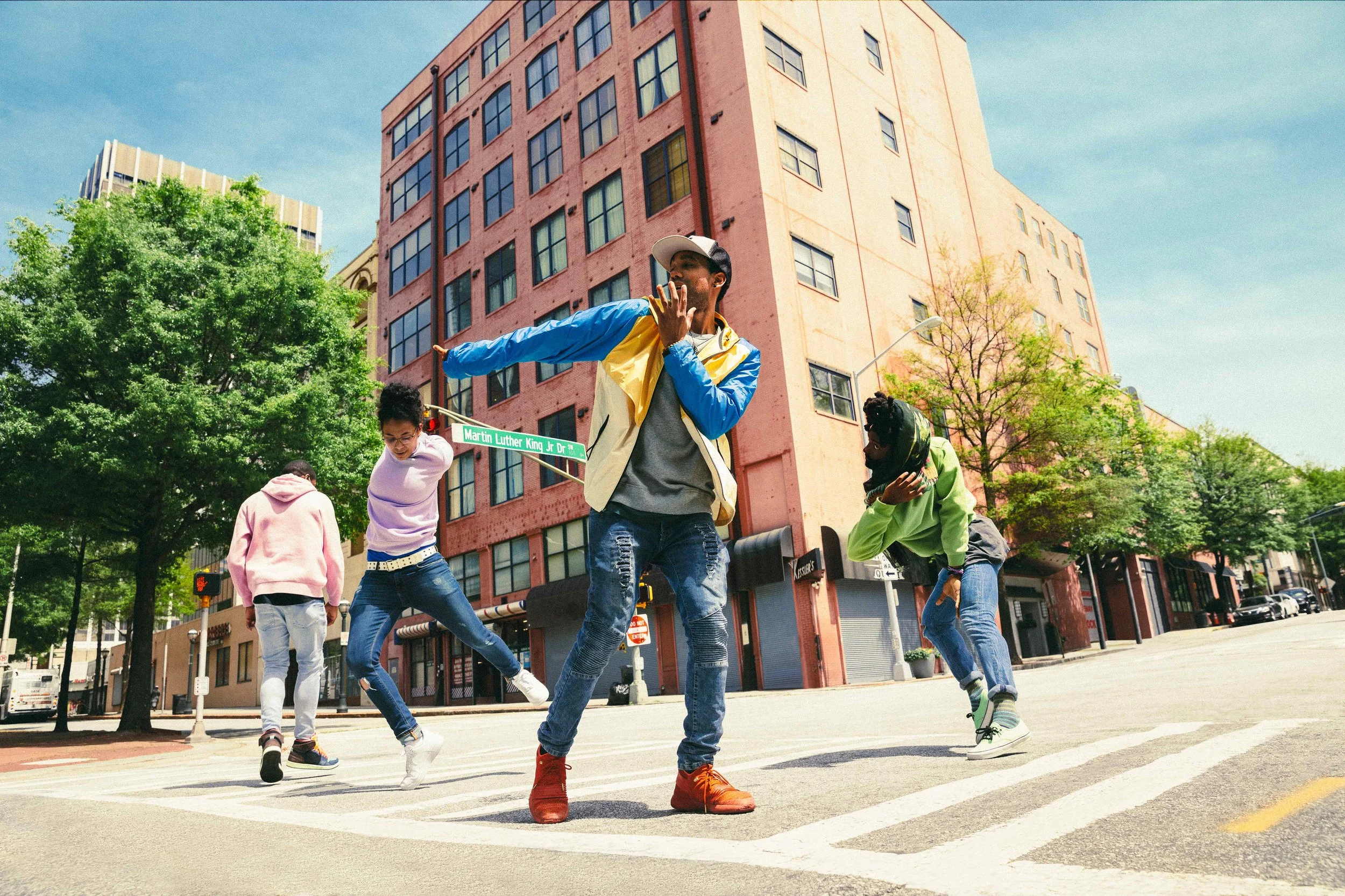 An image of four people dancing in a city intersection.