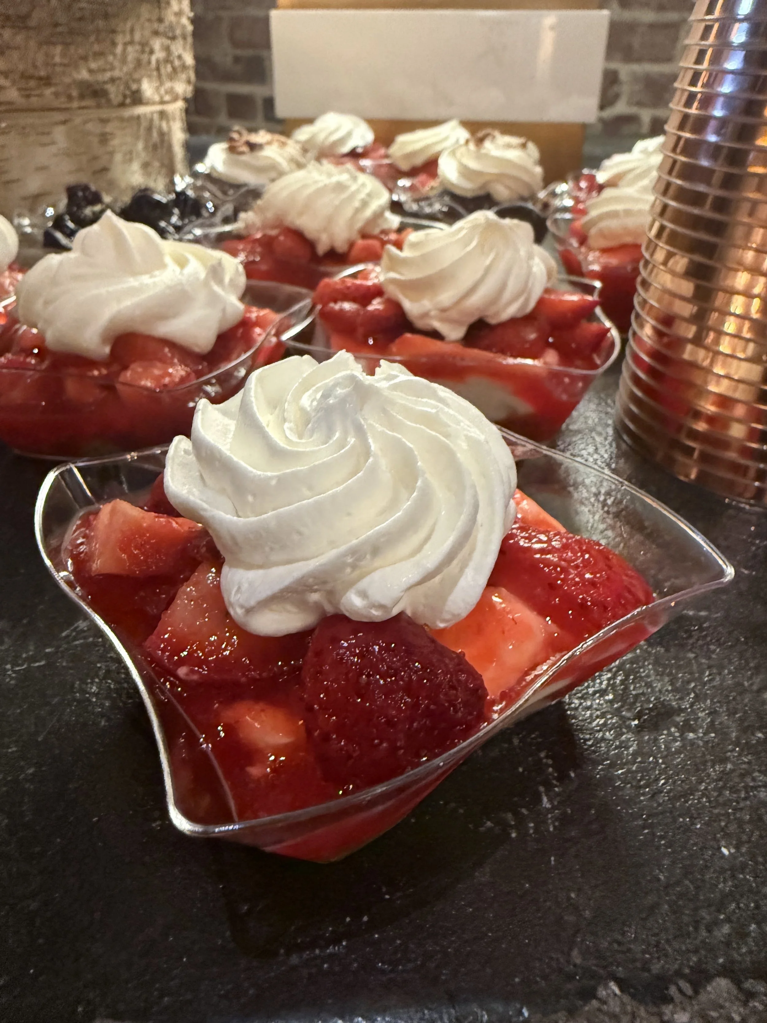 Dessert cups filled with strawberries, topped with whipped cream.