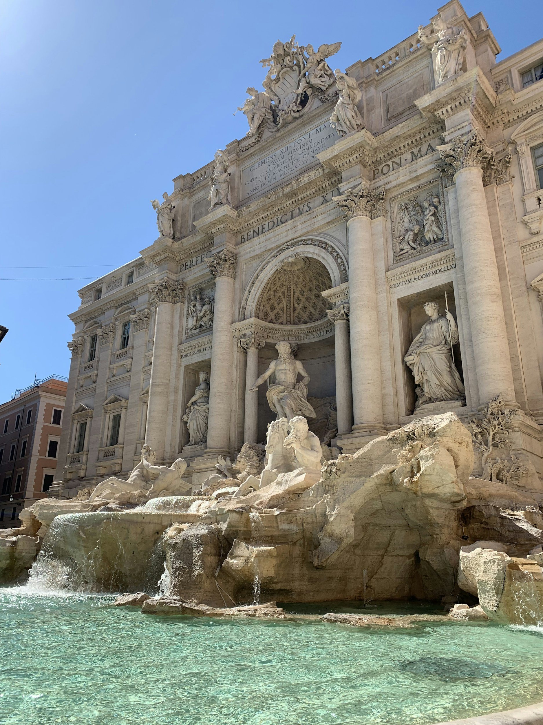 Statue fountain with sculptures and water in a historic building facade, likely the Trevi Fountain in Rome, Italy.