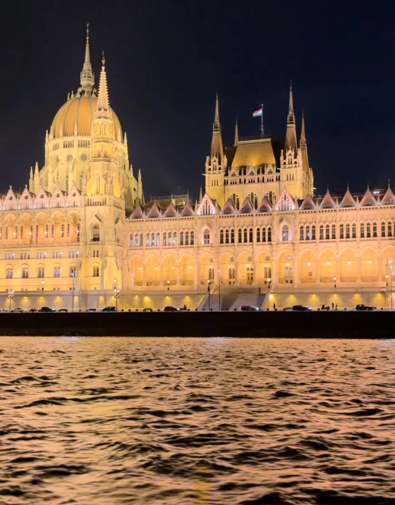 Night view of the illuminated Hungarian Parliament Building next to the Danube River from a european river cruise planned by travel by nikki