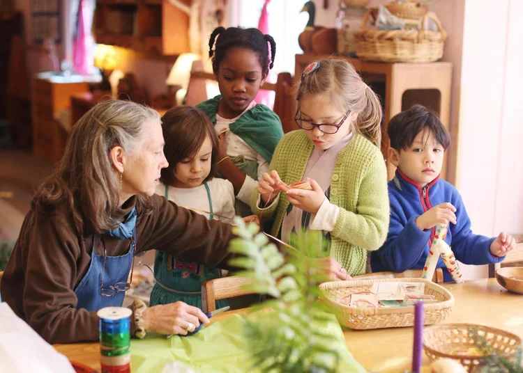Children and an older woman gather around a table engaged in a craft activity, with baskets and craft supplies visible.