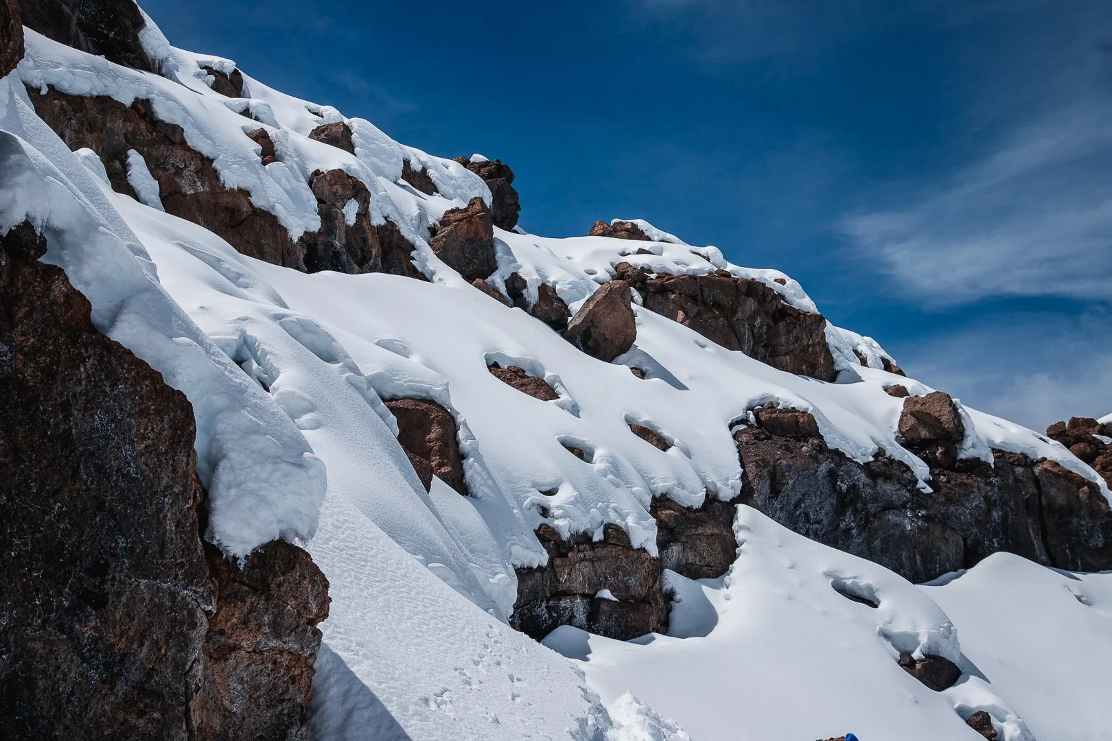 Snow-covered rocky mountains under a clear blue sky.