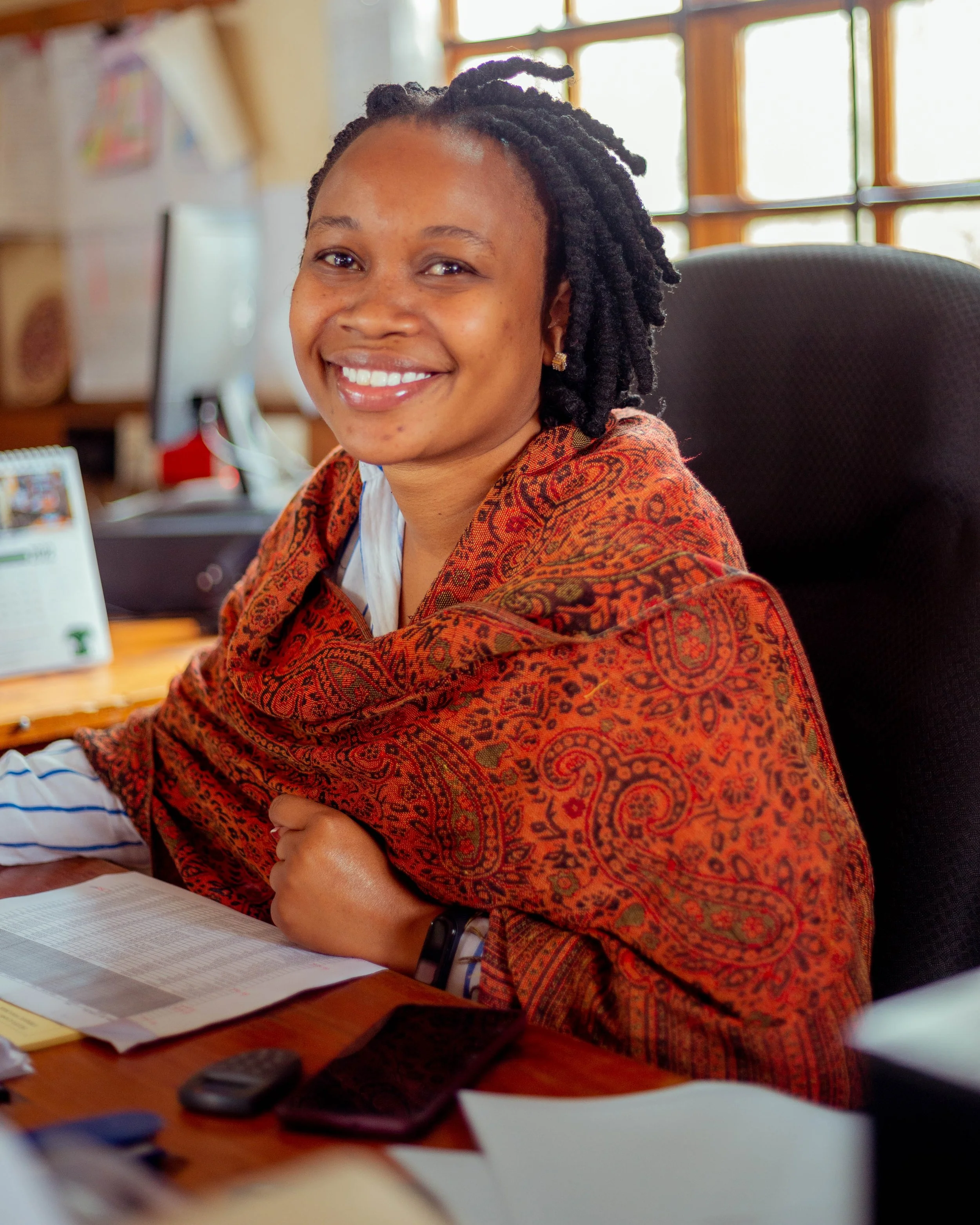 Lady with short dreads sitting at a desk smiling