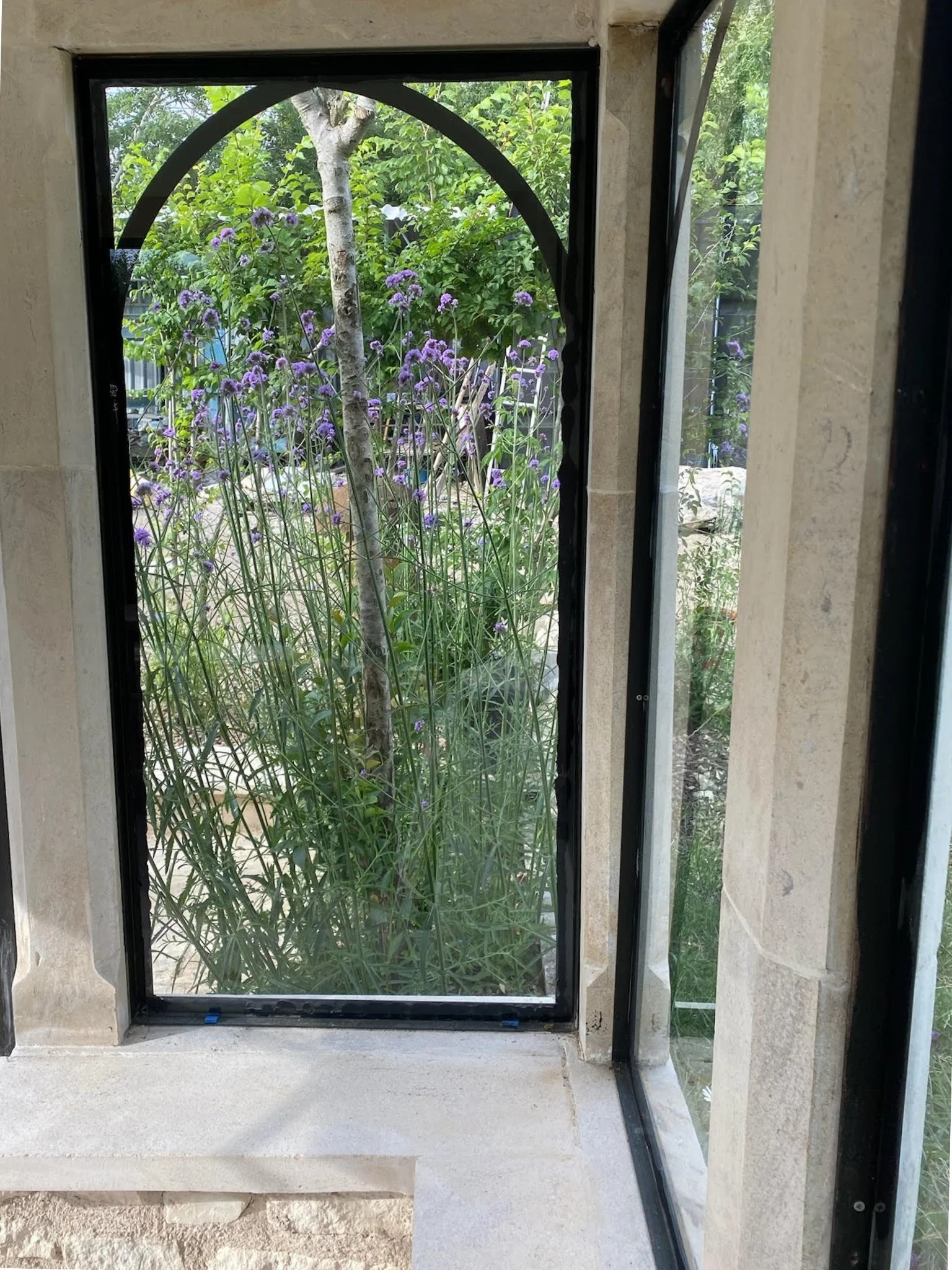 a mullion house window view showing the stone detail and black arched window frames
