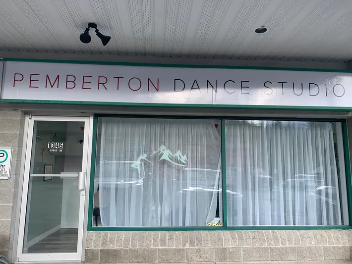 Exterior view of Pemberton Dance Studio with a sign, window with curtains, and a mountain and dancer silhouette decal.