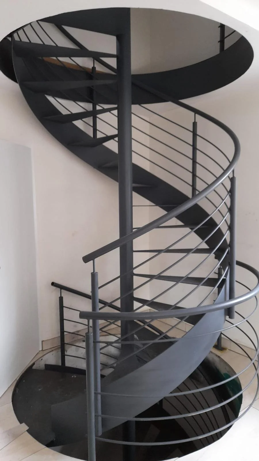 Moderne spiralförmige schwarze Treppe mit Metallgeländer in einem Innenraum.