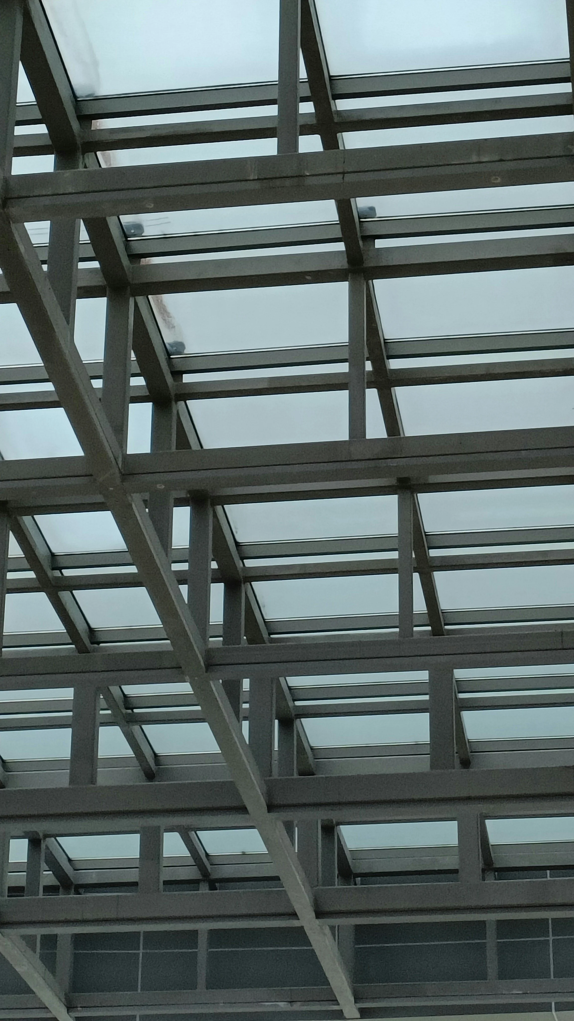 Blick auf eine moderne Glaskonstruktion mit Metallrahmen, vermutlich das Innere eines Gebäudes oder einer Veranda.