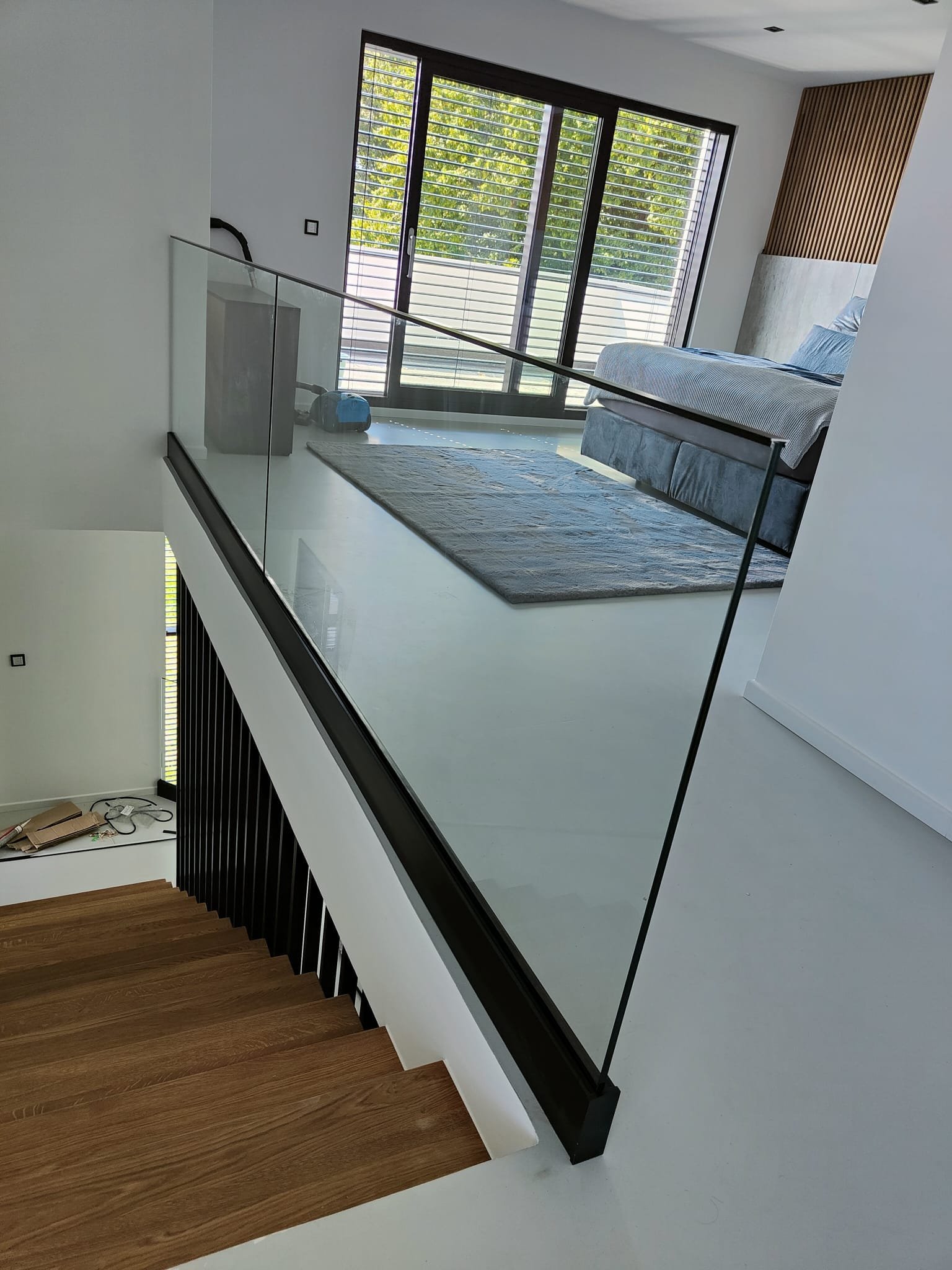 Innenansicht eines modernen Hauses mit Treppe, großer Glas-Schiebetür und Schlafzimmer im Hintergrund.