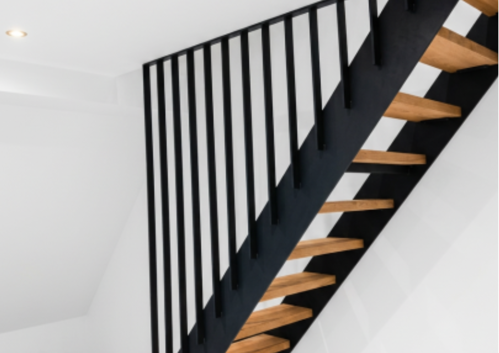 Moderner Innenraum mit schwarzer und naturbelassener Holztreppe und weißen Wänden.