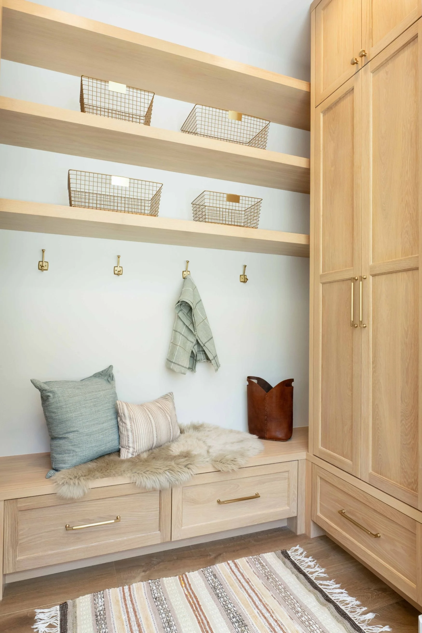 white oak mudroom cabinetry with tall cabinets and bench with floating shelves