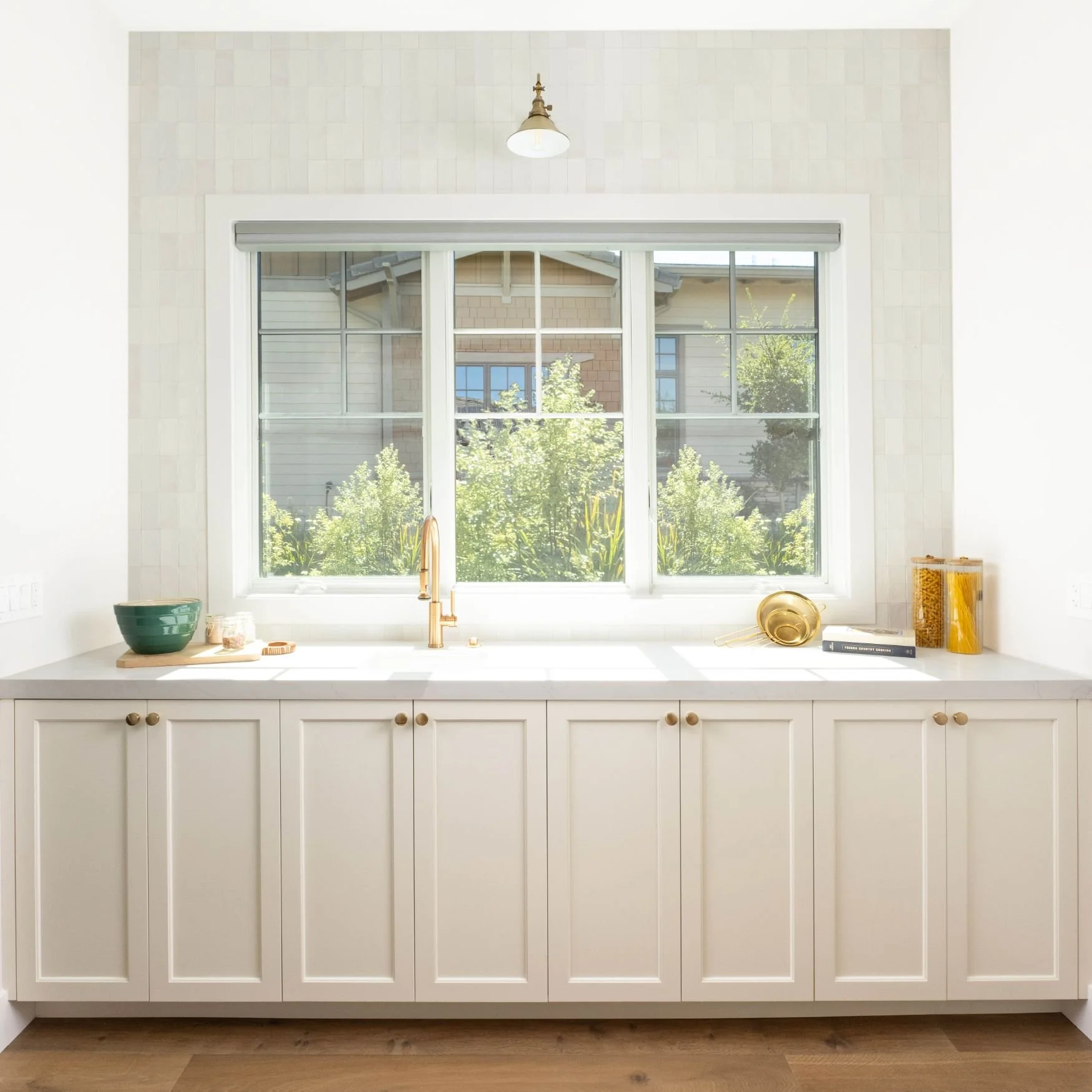 pantry cabinets with brass fixtures and large window and sink