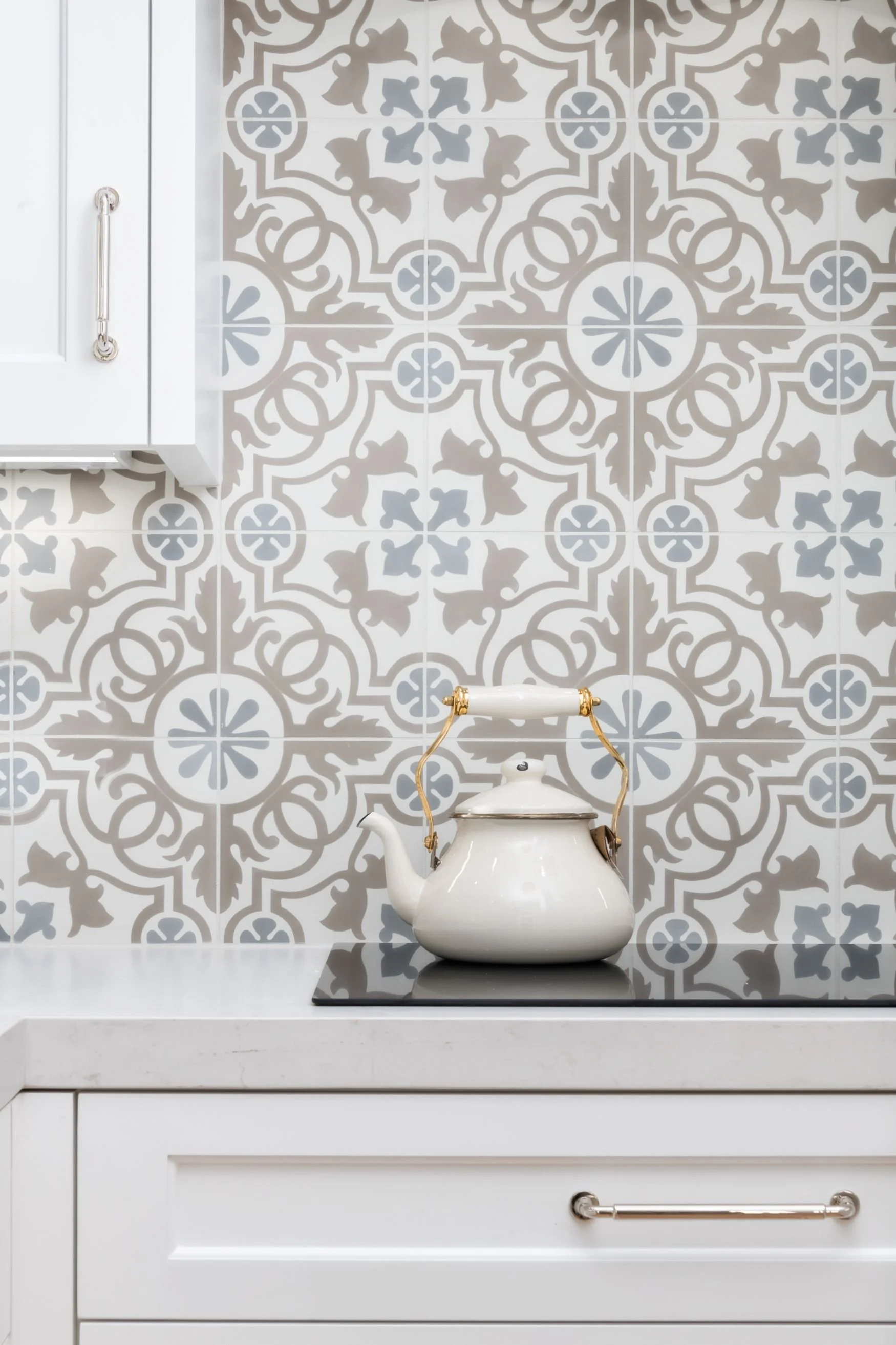 Pattern tile kitchen backsplash with white and brass tea kettle