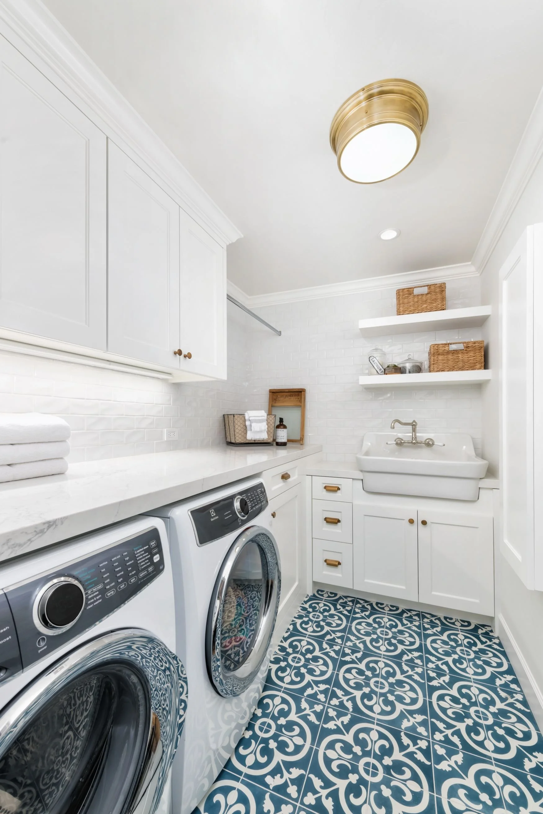 Laundry room with blue pattern tile and white cabinets