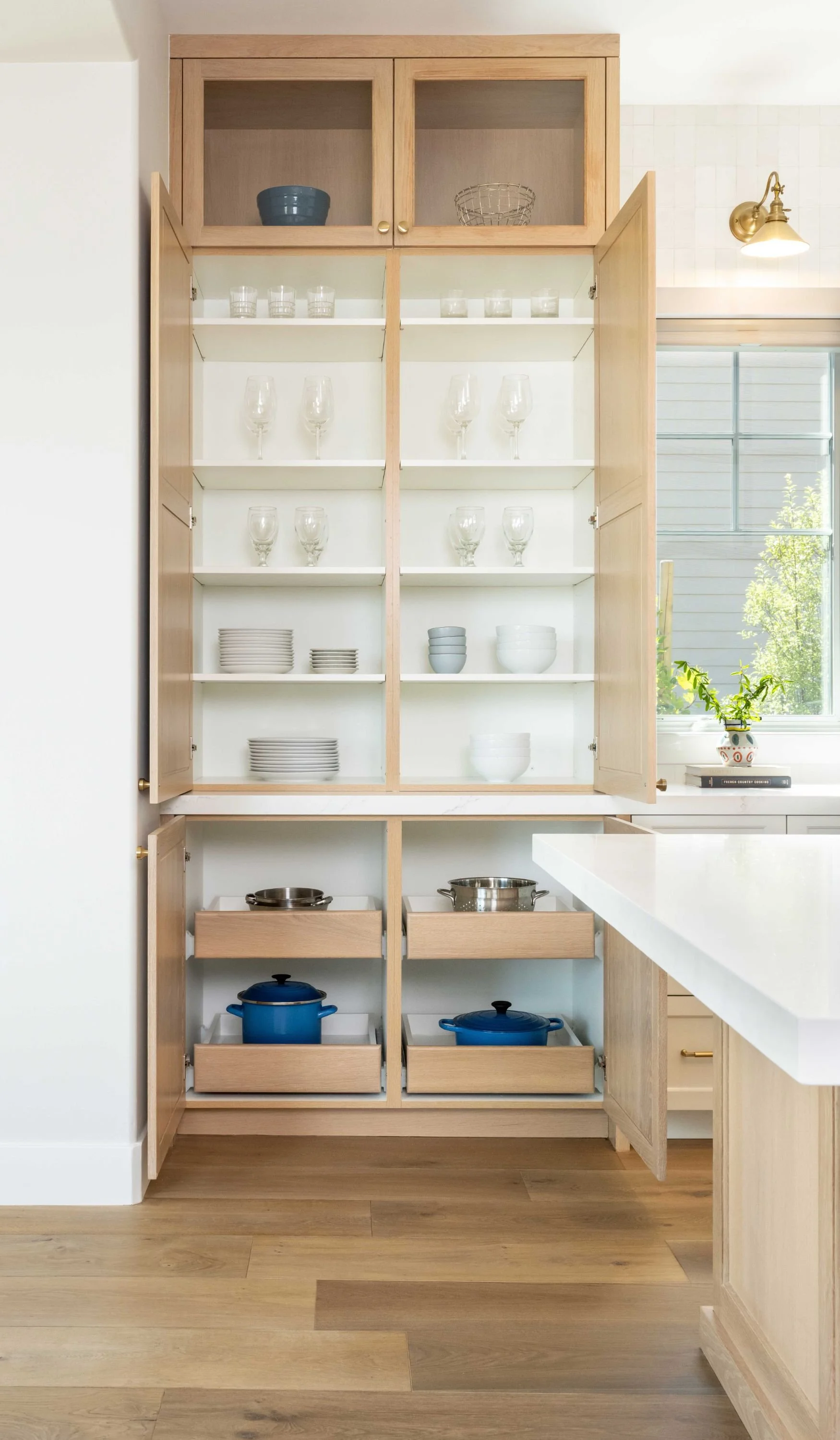 Pantry cabinet open showing storage with white oak cabinets and flooring