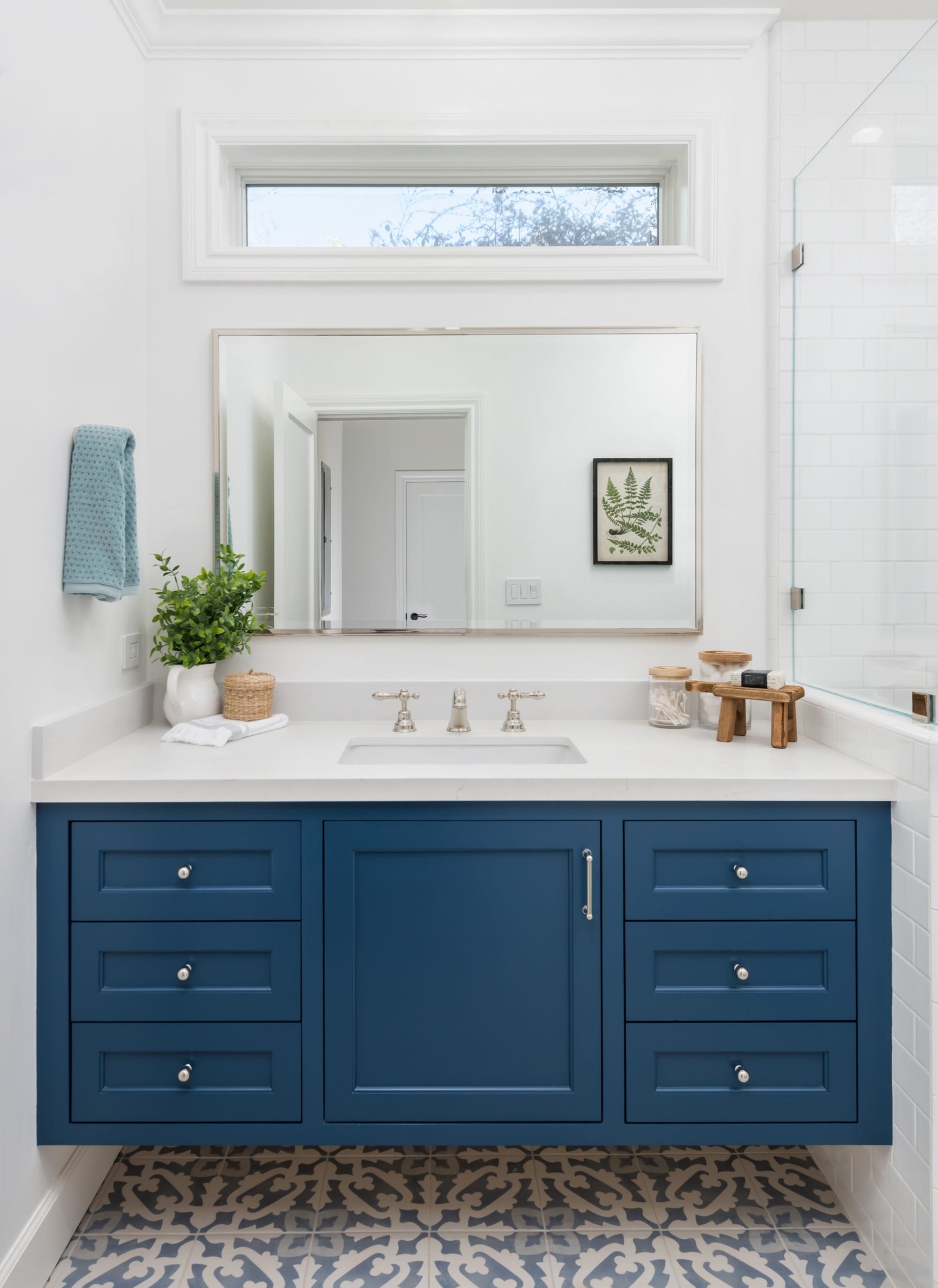 Blue floating vanity with pattern blue tile floor and transom window