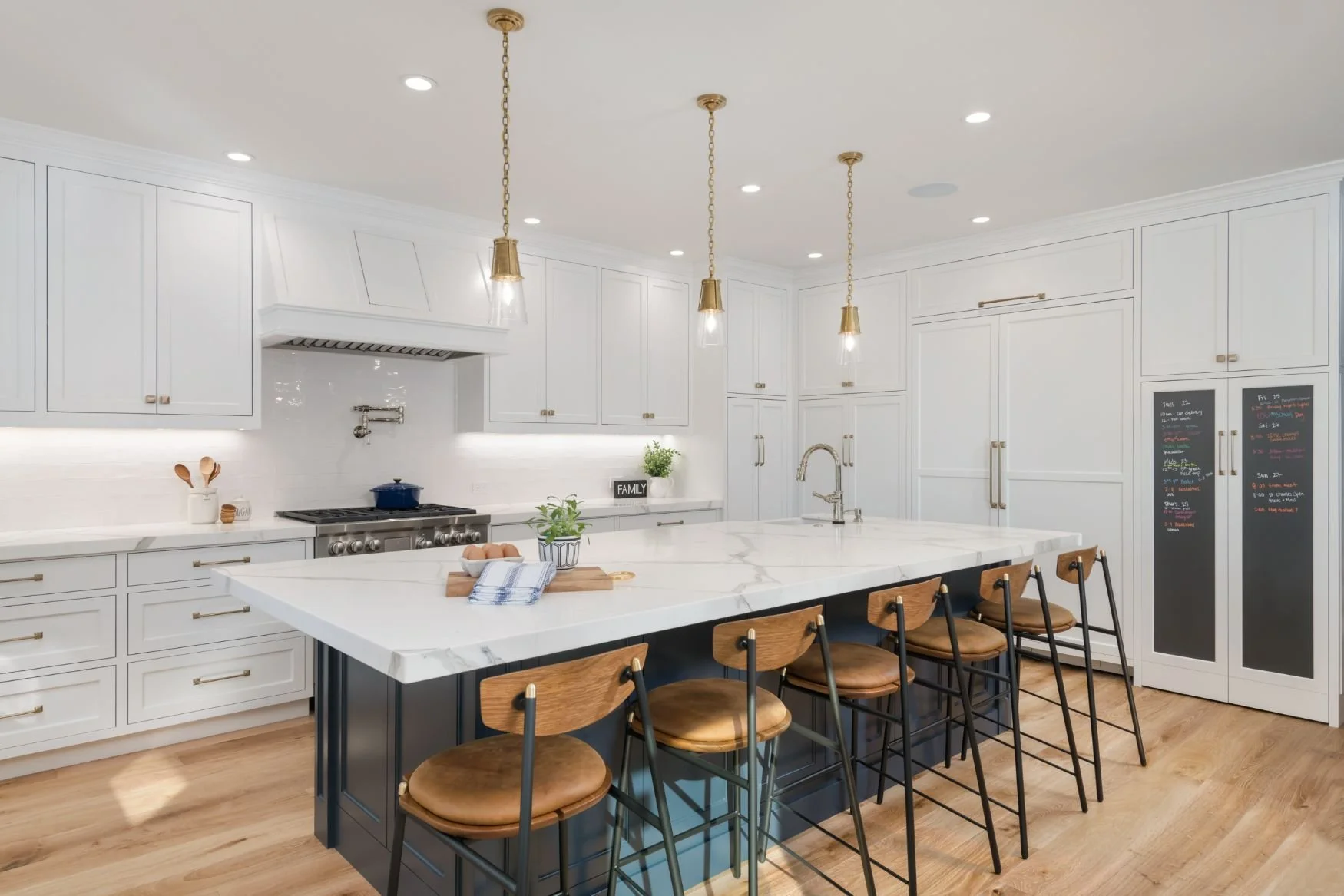 large kitchen with large island in hale navy, white cabinets and brass lighting