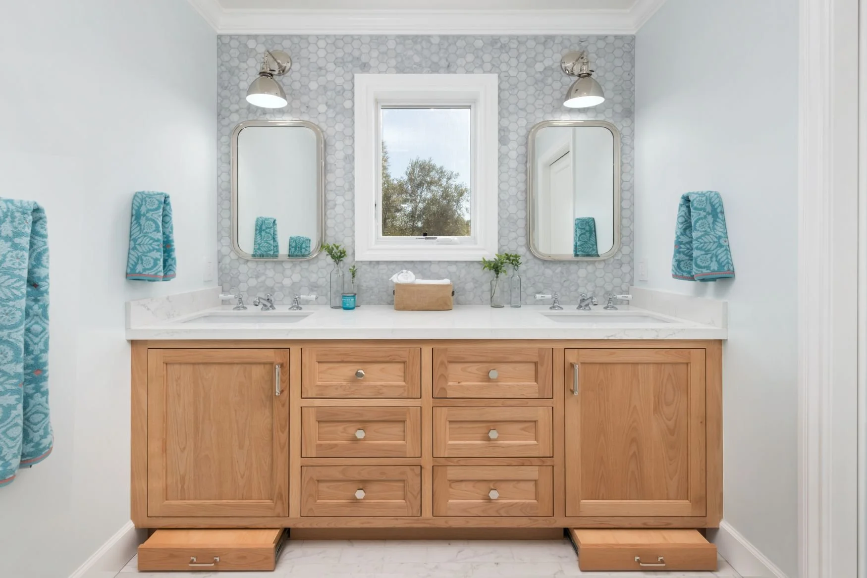 White oak vanity with pull out step stools for kids with Carrara marble floor and backsplash
