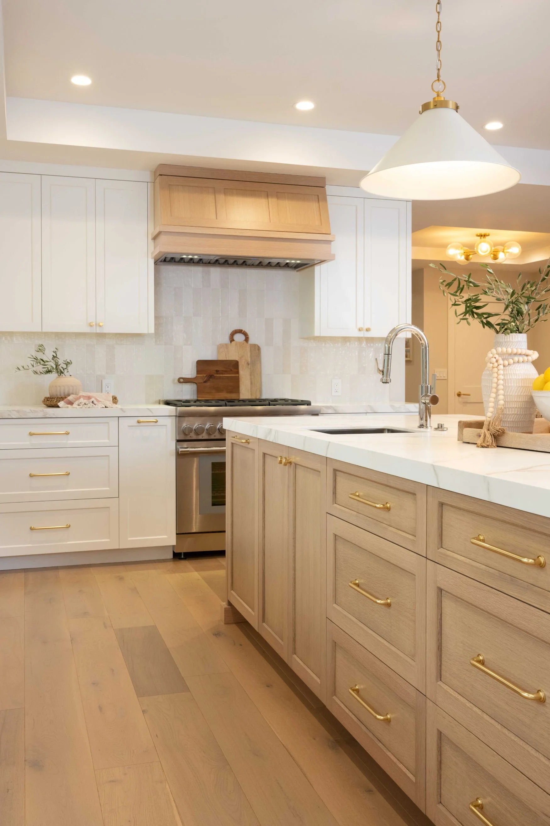Kitchen with white oak and white cabinetry, brass hardware and lighting and white tile backsplash