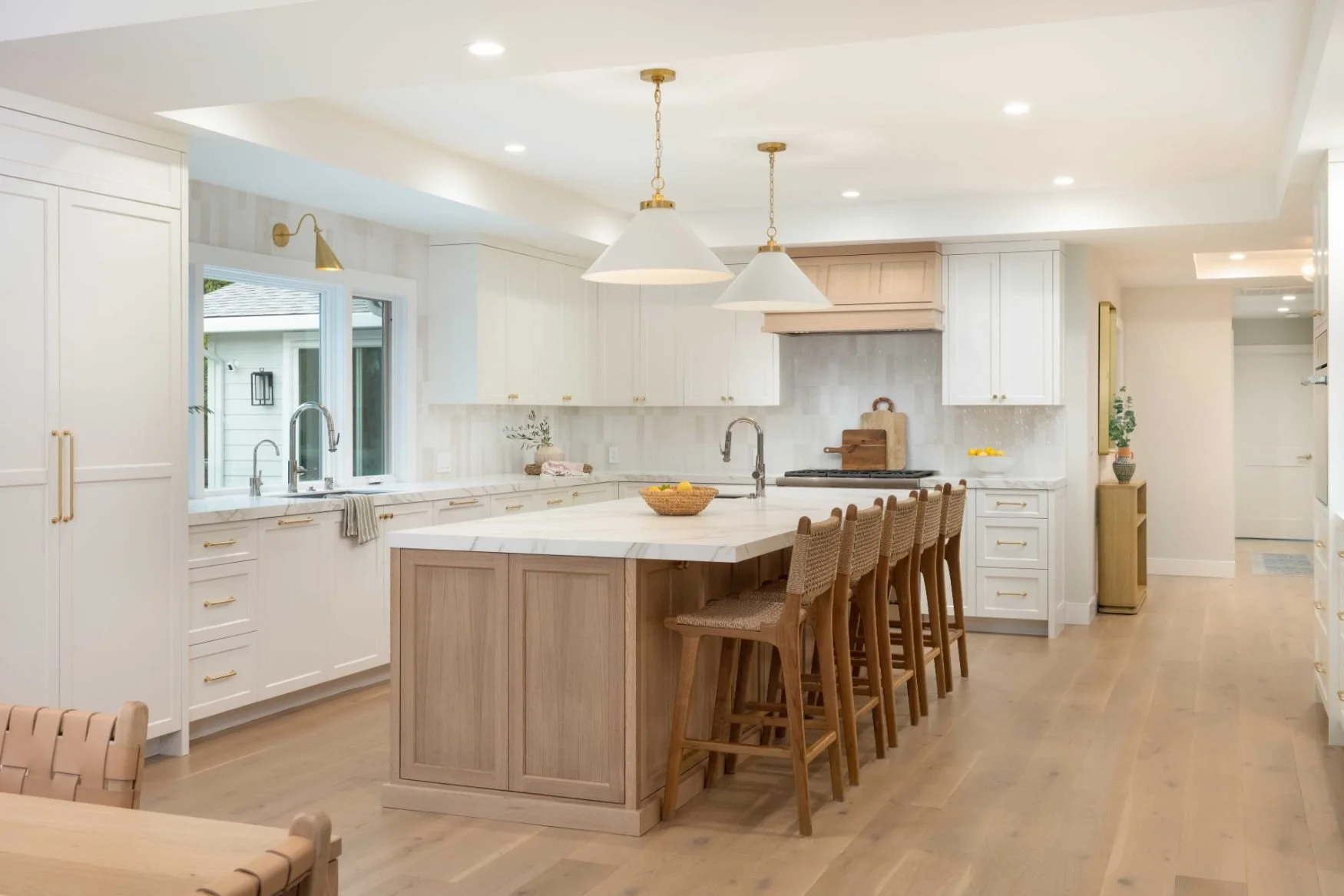 Two tone large kitchen with white and oak cabinets, white countertops and brass lighting