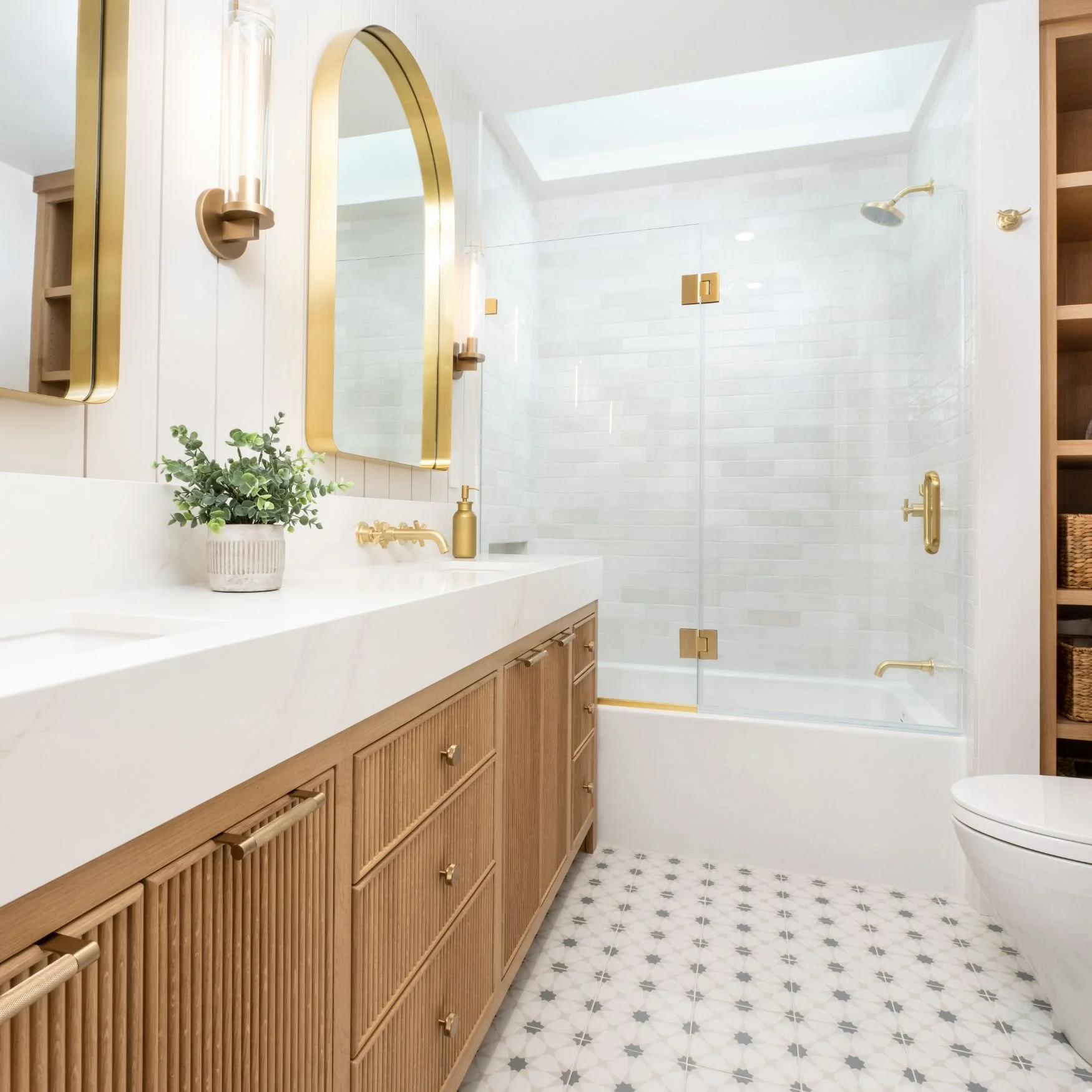 Hall bathroom with oak vanity, pattern tile, tub
