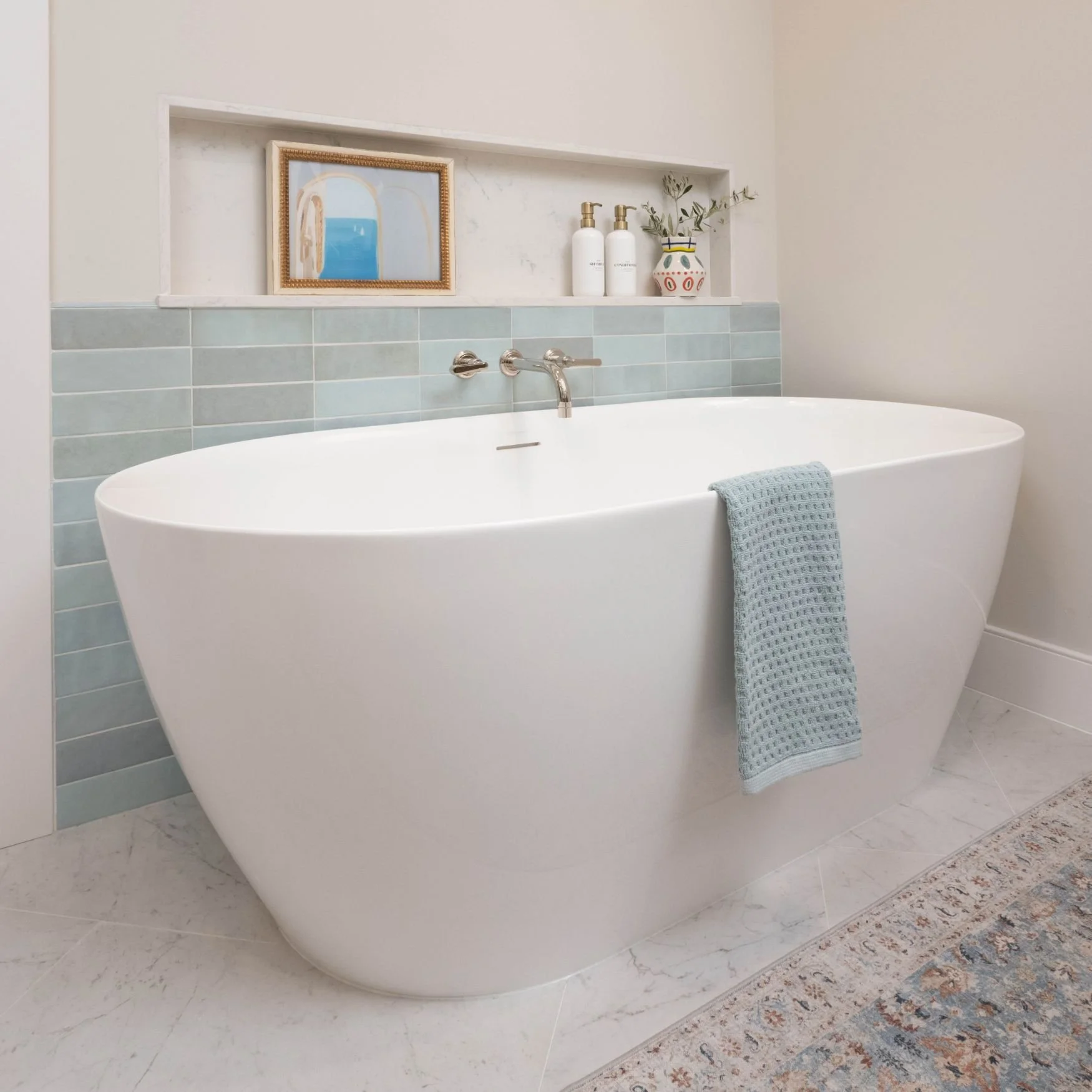 Freestanding tub with blue tile surround and wide niche for storage