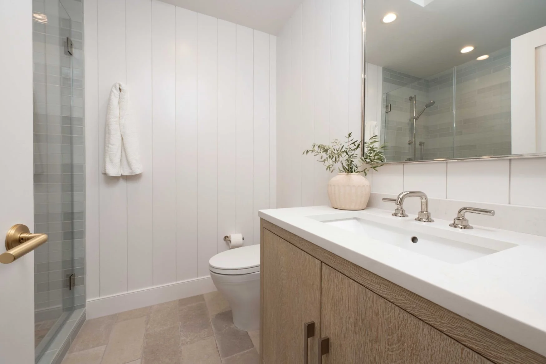 small bathroom with wood vanity, tile floor and paneled walls