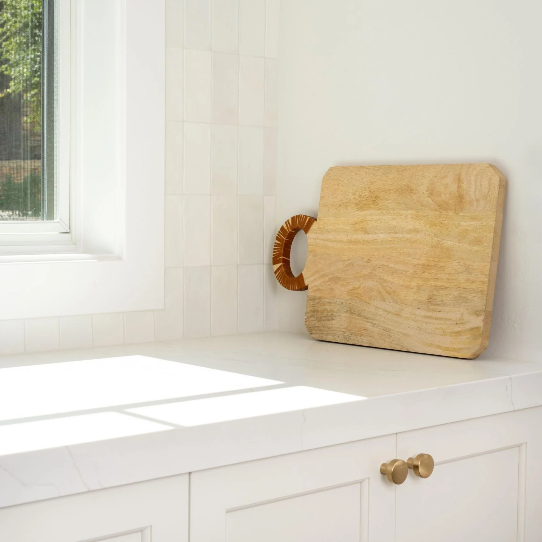 white cabinetry with brass knobs, white quartz countertop and white zellige backsplash tile